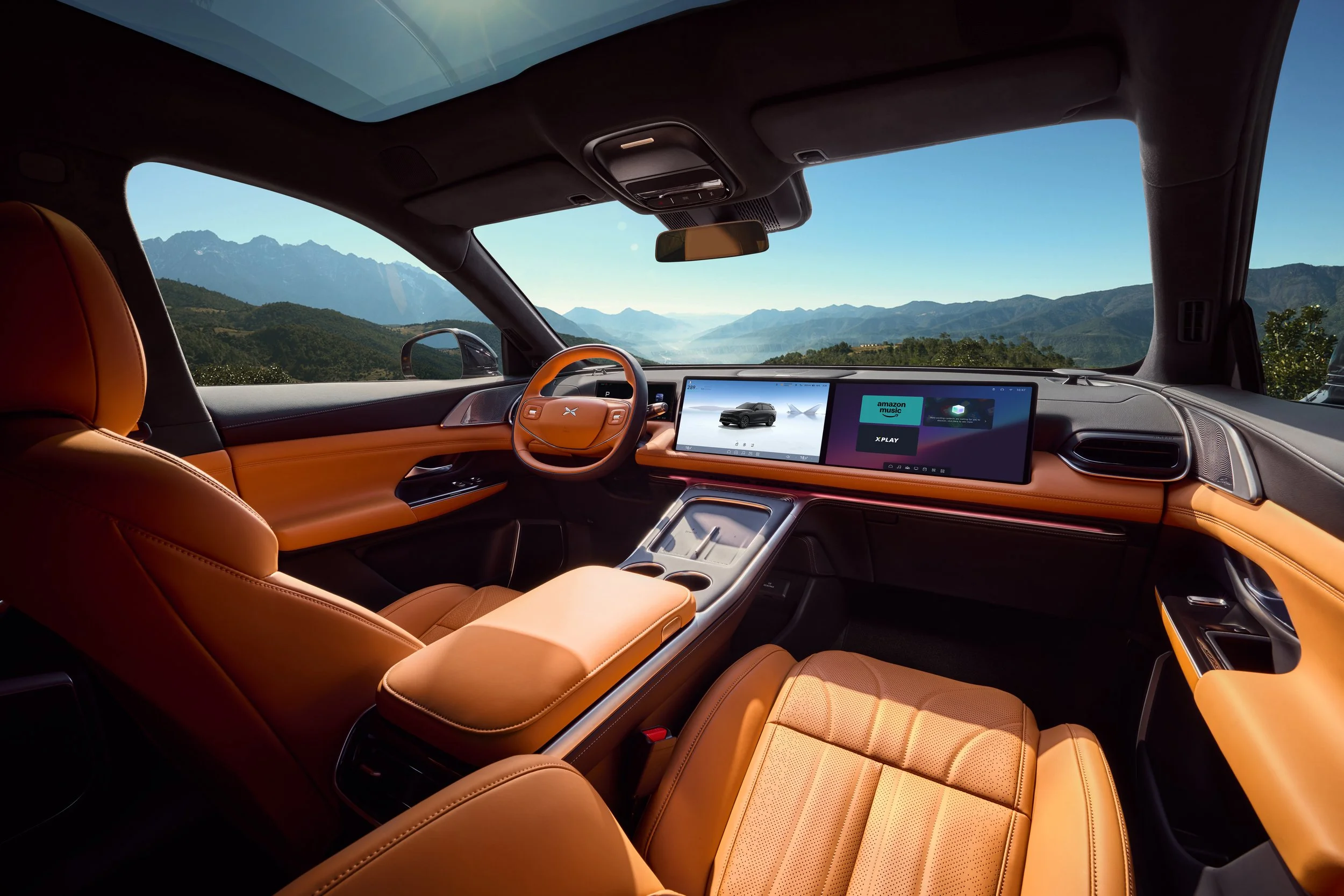 Intérieur d'une voiture moderne avec un tableau de bord numérique, sièges en cuir marron, vue d'un paysage montagneux à l'extérieur.