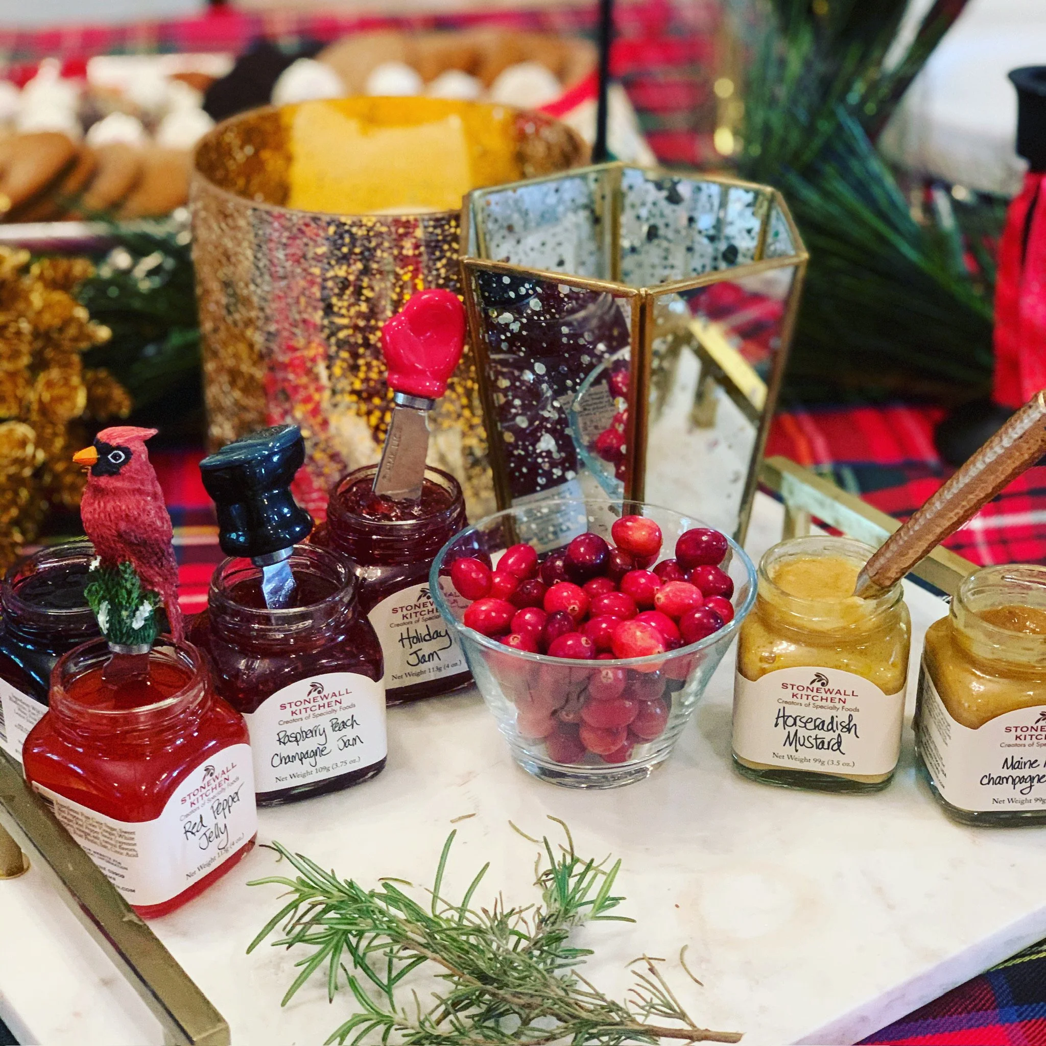 Holiday-themed display of jams, honey, fresh cranberries, and decorative accents on a table.