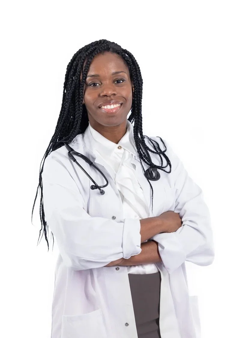 Médecin afro-américaine aux cheveux tressés, portant une blouse blanche et un stéthoscope, souriante, les bras croisés.