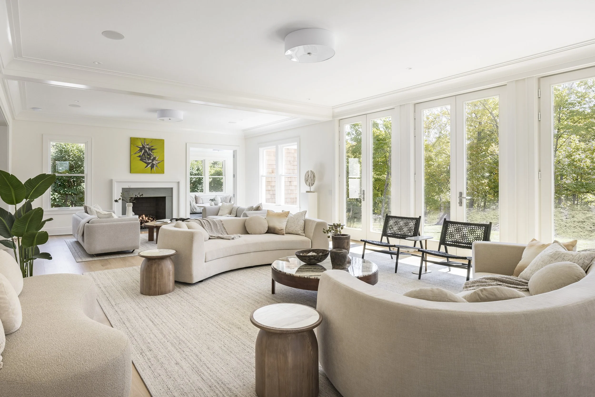 Bright, airy living room with large windows and a modern, neutral-colored sofa set, a fireplace, and minimalist decor.