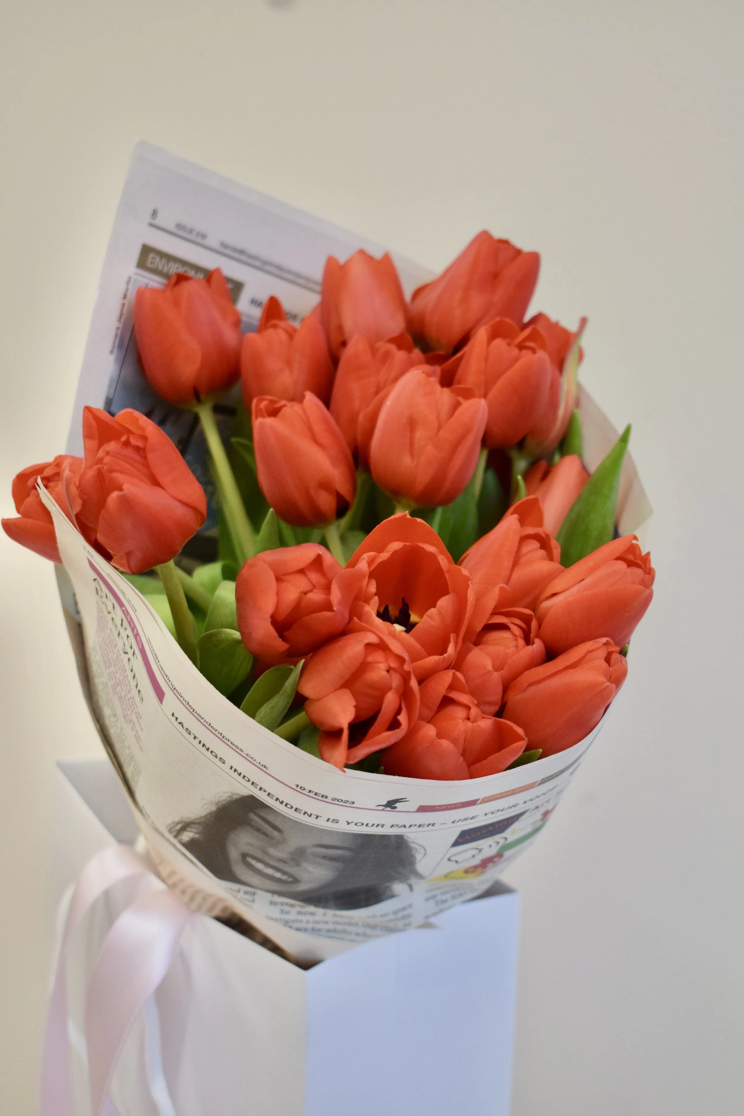A bouquet of bright red tulips for Valentines Day, wrapped in Hastings Independent newspaper