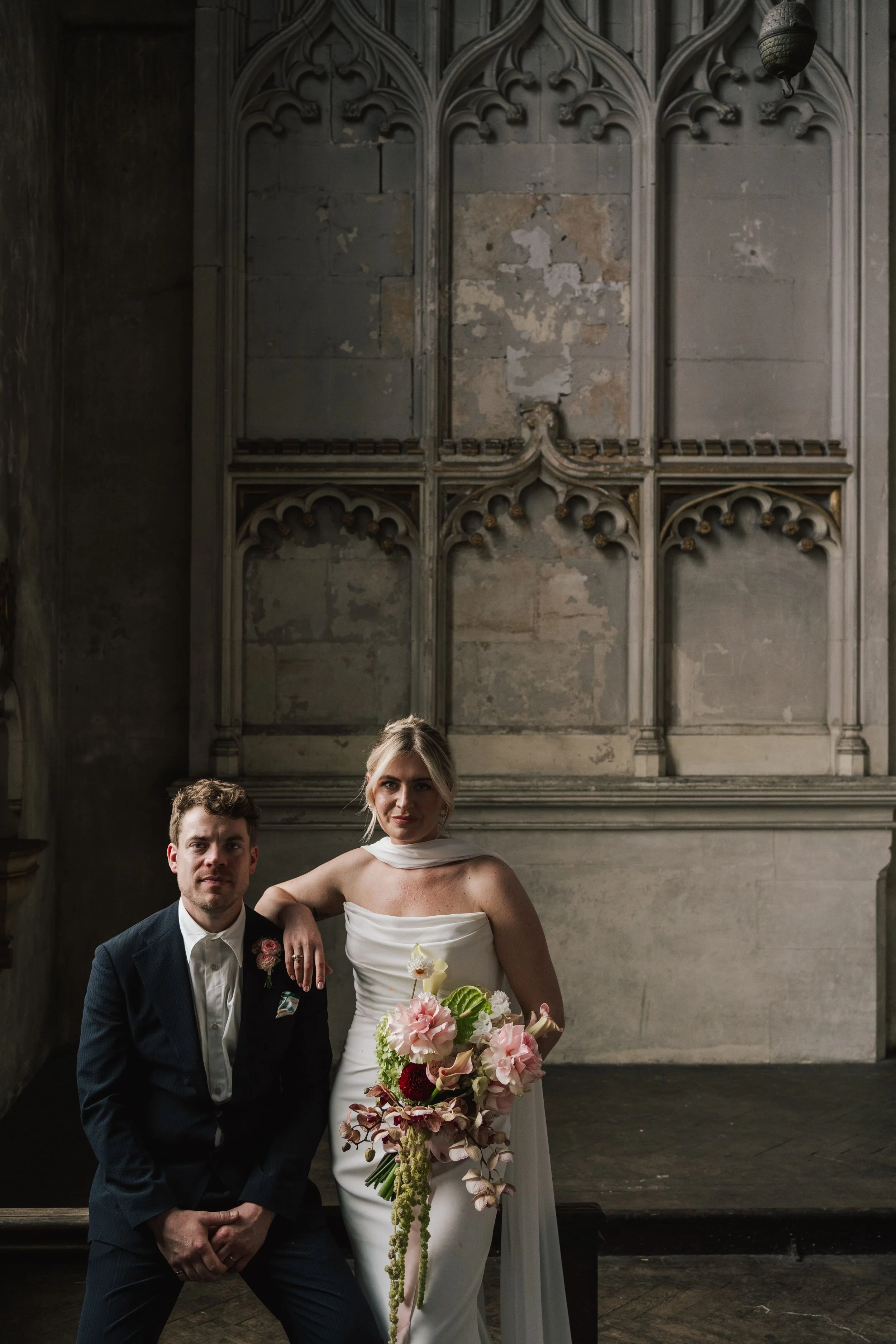 A bride & groom posing for a portrait photo at the HAC Bow in London, the bride is holding a modern wedding bouquet