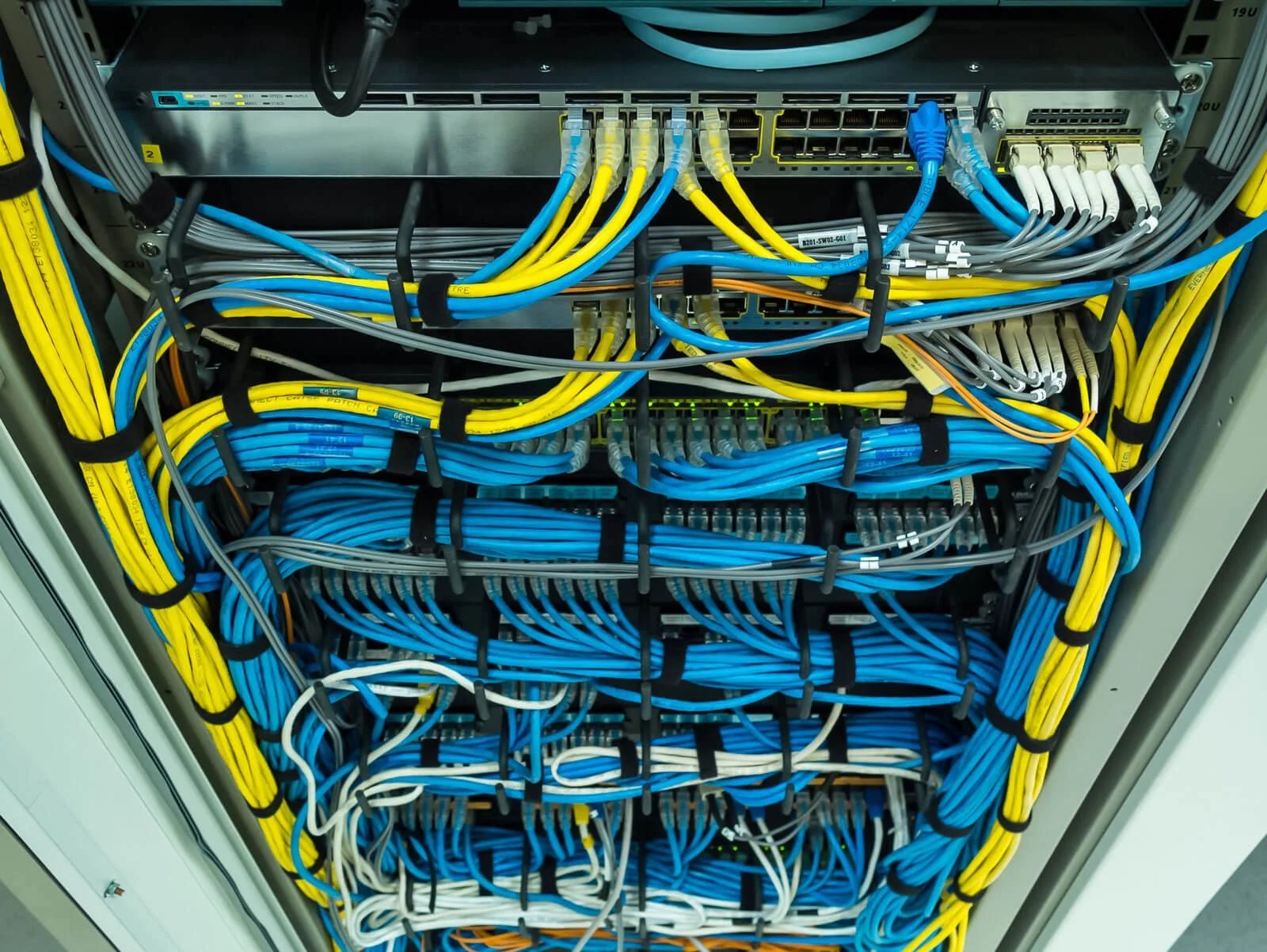 A server rack filled with organized yellow, blue, gray, white, and orange network cables connected to network equipment.
