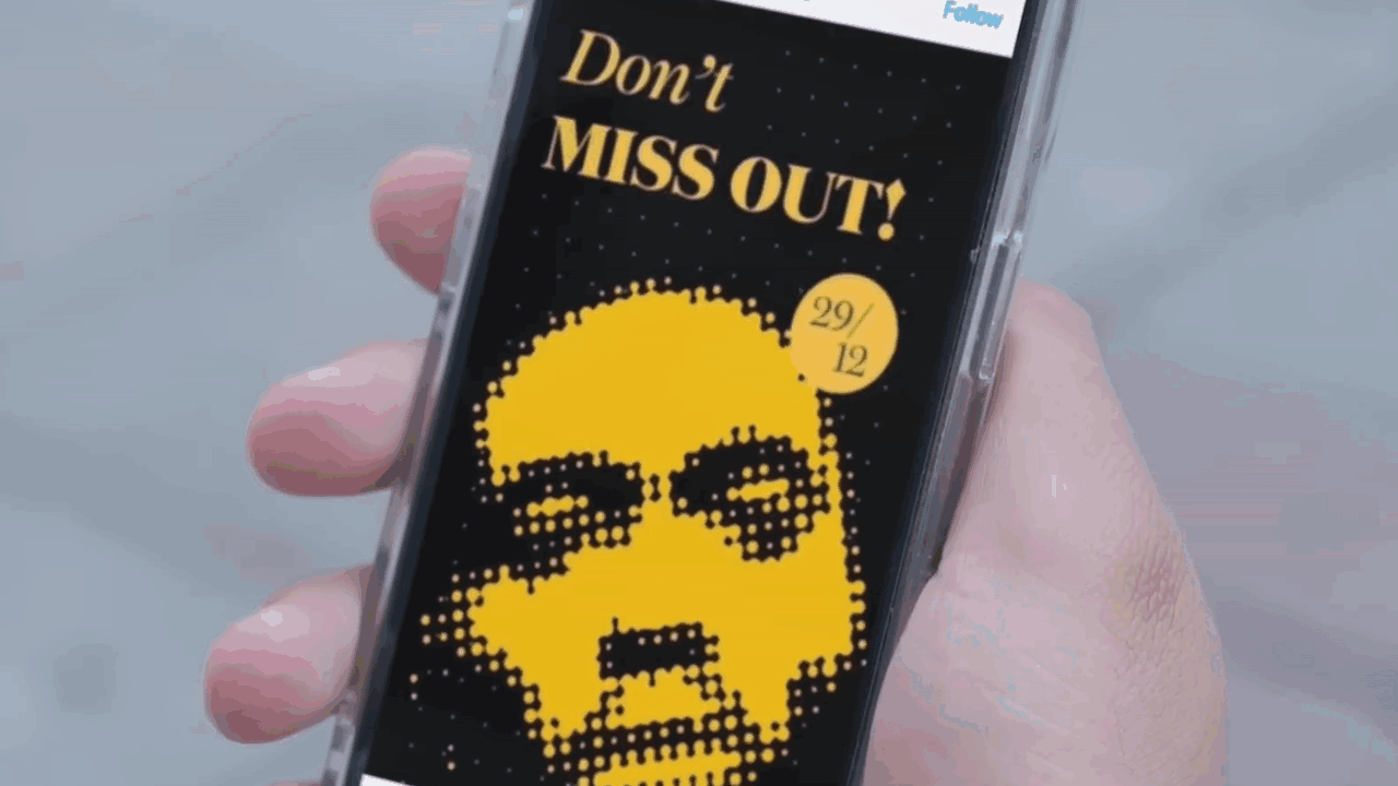 A smartphone held in hand displaying a digital graphic with a pixelated yellow skull and sunglasses, with the text 'Don't MISS OUT!' and a yellow circle showing the date '29/12'.