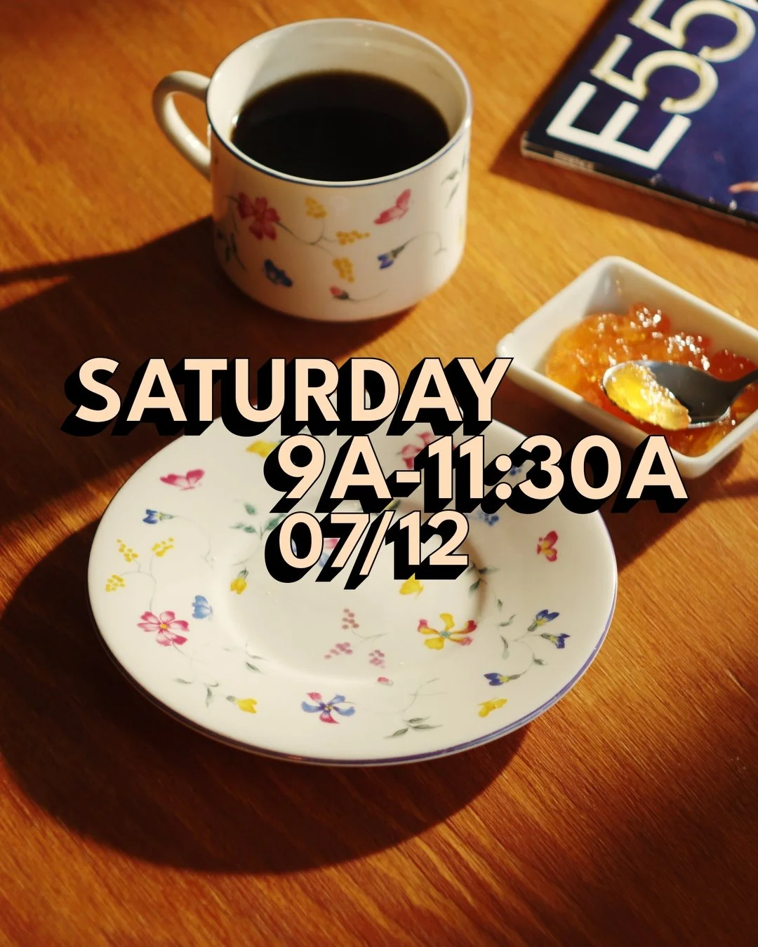 A cup of black coffee, a small bowl of orange marmalade with a spoon, and a empty floral-patterned plate on a wooden table. Part of a book with 'E55' visible is in the corner.
