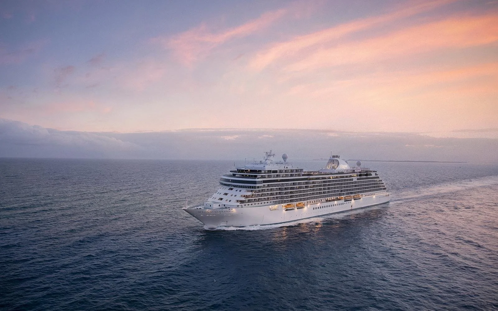 A large white cruise ship sailing on the ocean during sunset