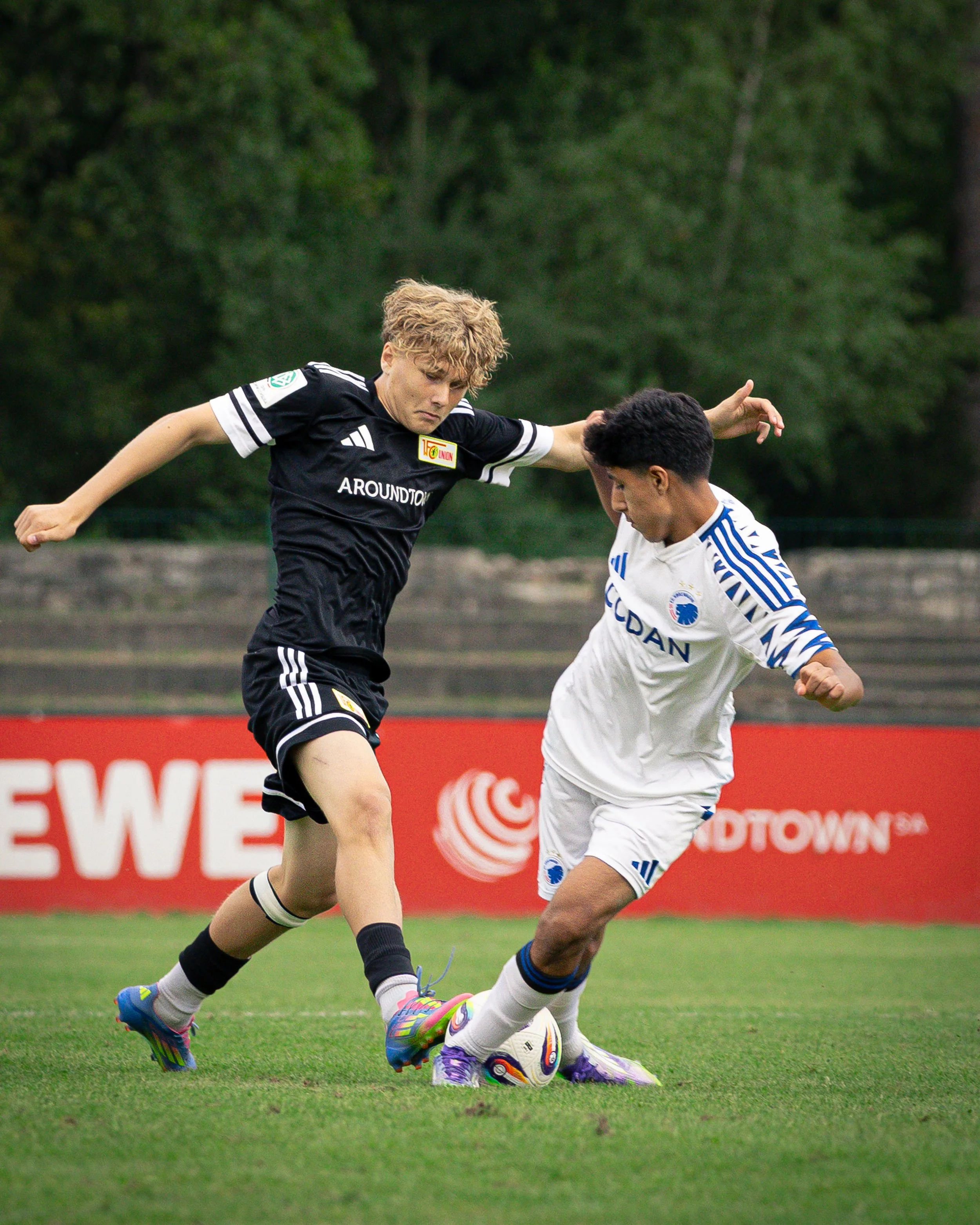 Two soccer players competing for the ball on a grass field.