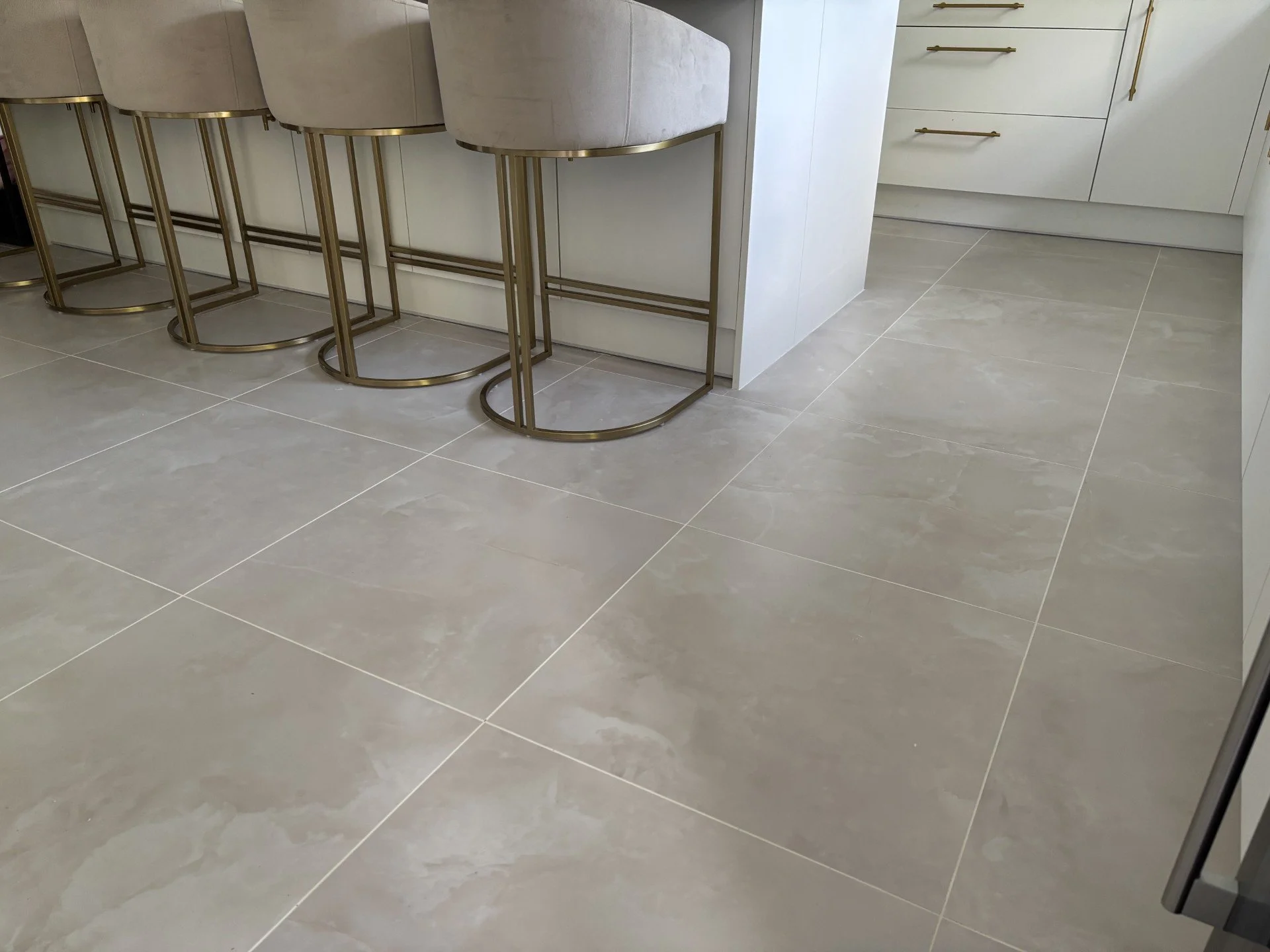 Grey polished porcelain floor tiling in a modern kitchen with island and bar seating