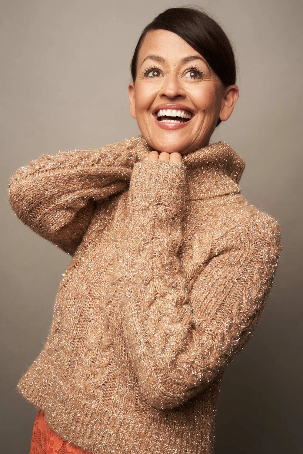Yve Rojas smiling and looking upwards, wearing a cozy, shimmery beige sweater.
