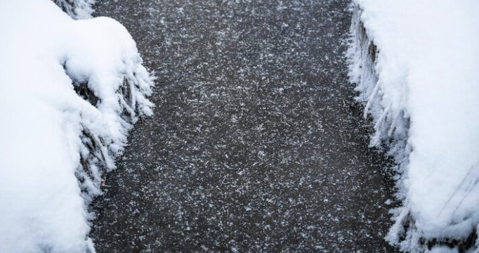 Snow-covered pavement with ice and snow on the edges.