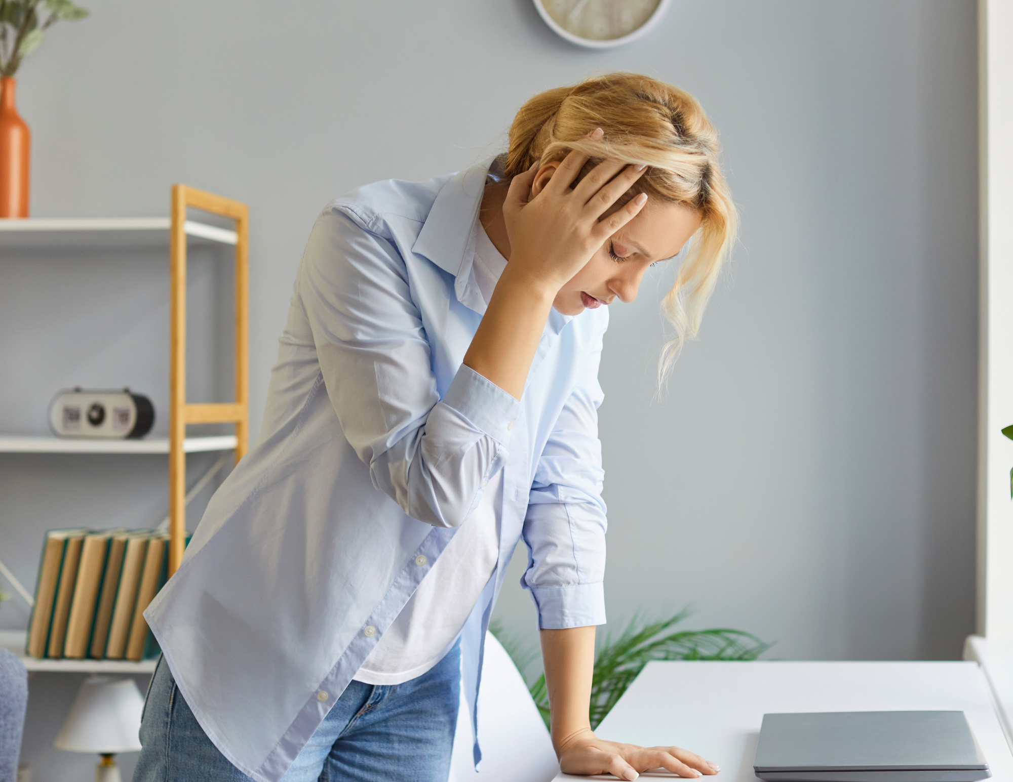 Woman experiencing dizziness and fatigue while standing at desk, illustrating symptoms of POTS (Postural Orthostatic Tachycardia Syndrome) in adults seeking diagnosis in NYC