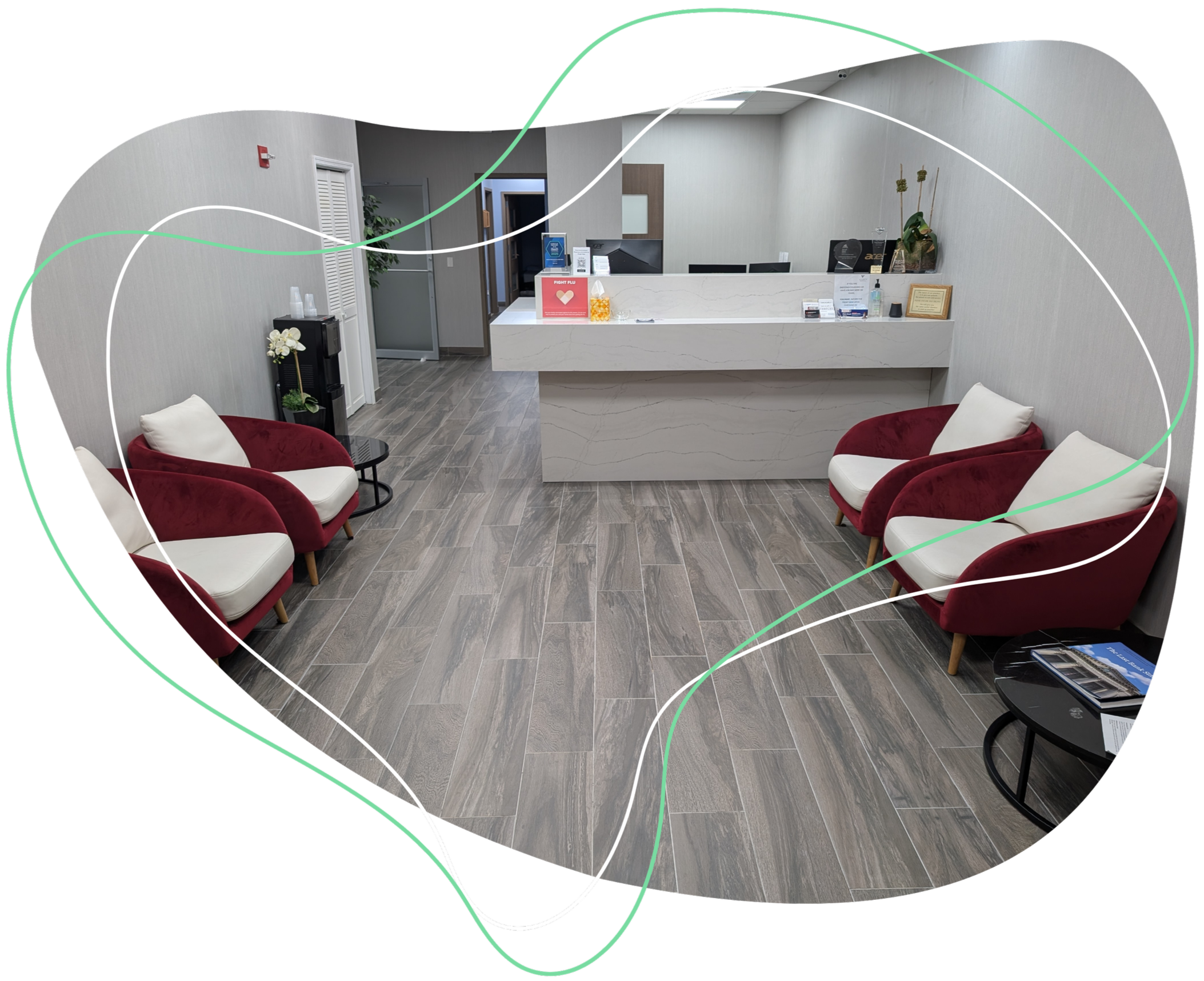 A modern reception area with a white marble counter, six red velvet armchairs with white cushions, a small black side table, and a wooden door. The floor is covered with grayish wood tiles, and the wall behind the counter has light gray textured wallpaper.