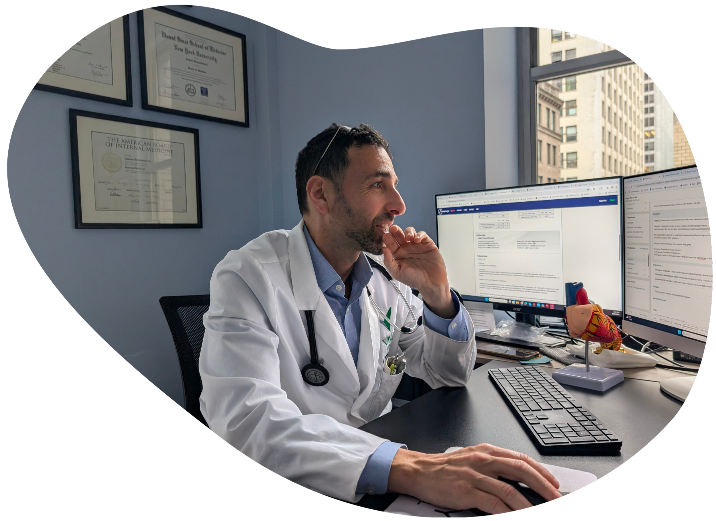 Cardiologist working in a medical office, reviewing patient information at a desk with diagnostic equipment and heart model nearby.