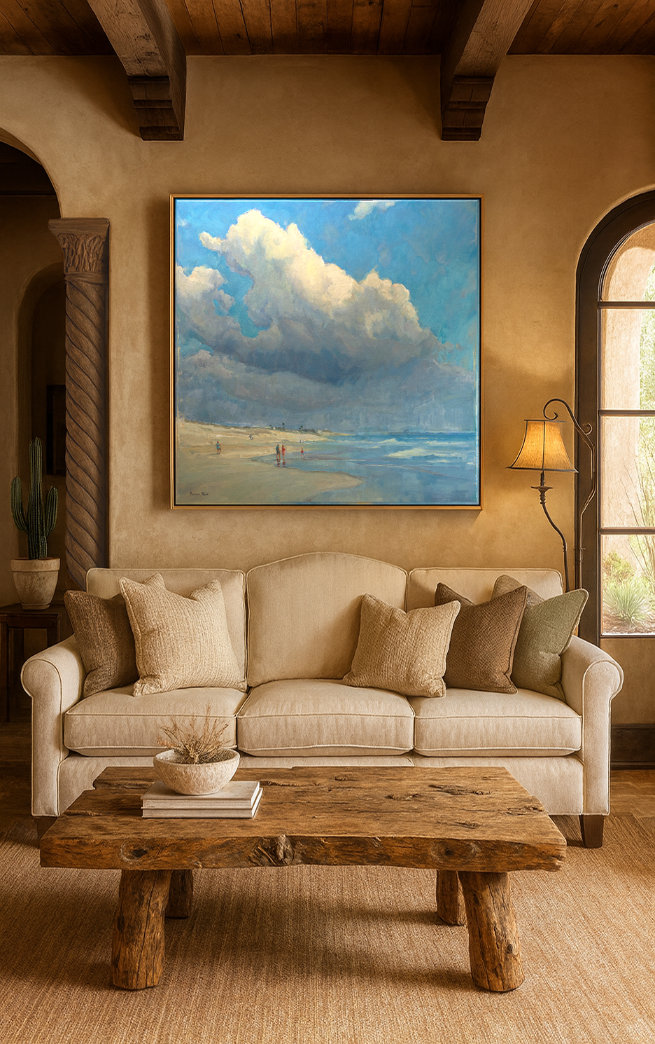 Sea of Clouds 36x36 beach cloudscape painting in gold frame displayed above beige sofa in rustic Southwest living room with exposed wood beams and arched doorways
