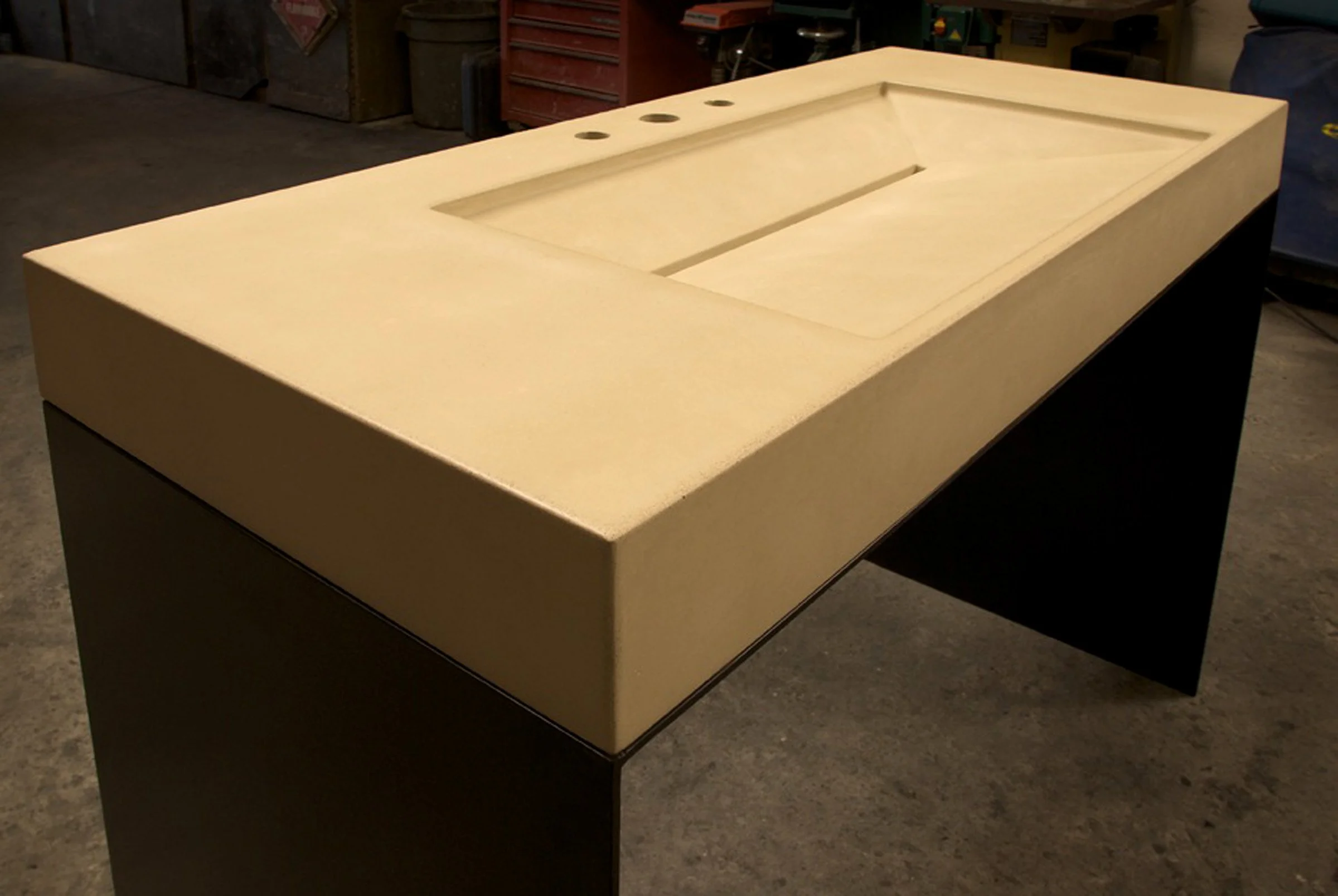 Modern concrete sink with slot drain and blackened steel base design.