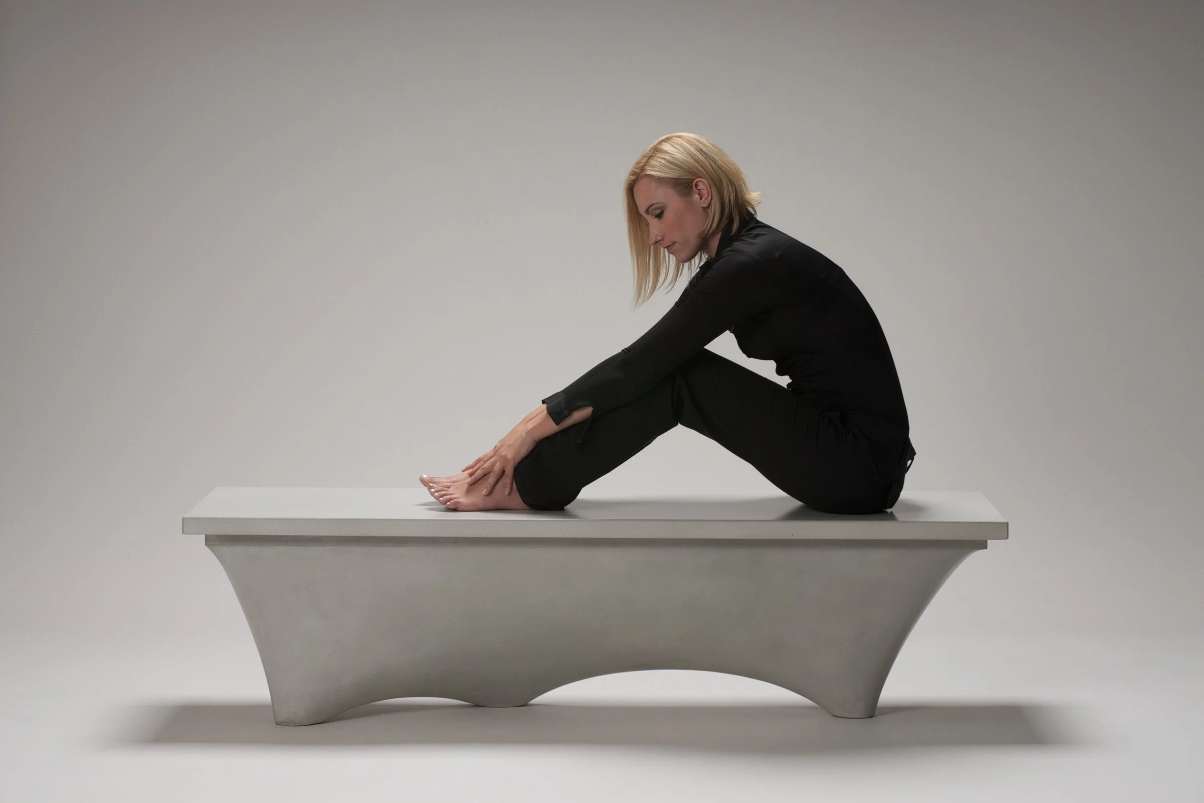 Custom fabric-formed concrete bench in clay GFRC. Hollow construction for lightweight strength, easily bolted for outdoor or public installations.
