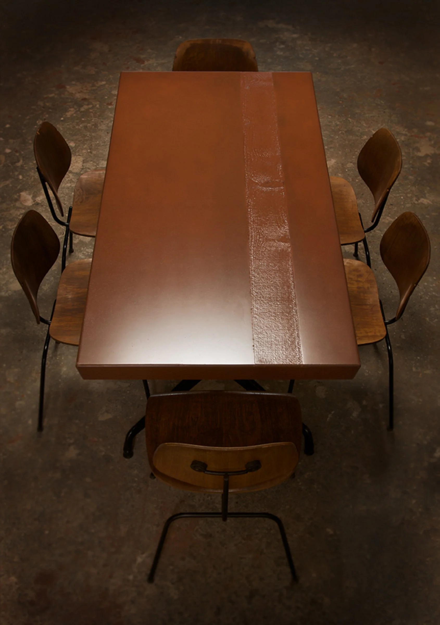 Handcrafted GFRC concrete dining table in Cherokee Red. Features custom edge profile, wood grain texture, and healthy, non-toxic sealer with Eames base pairing.