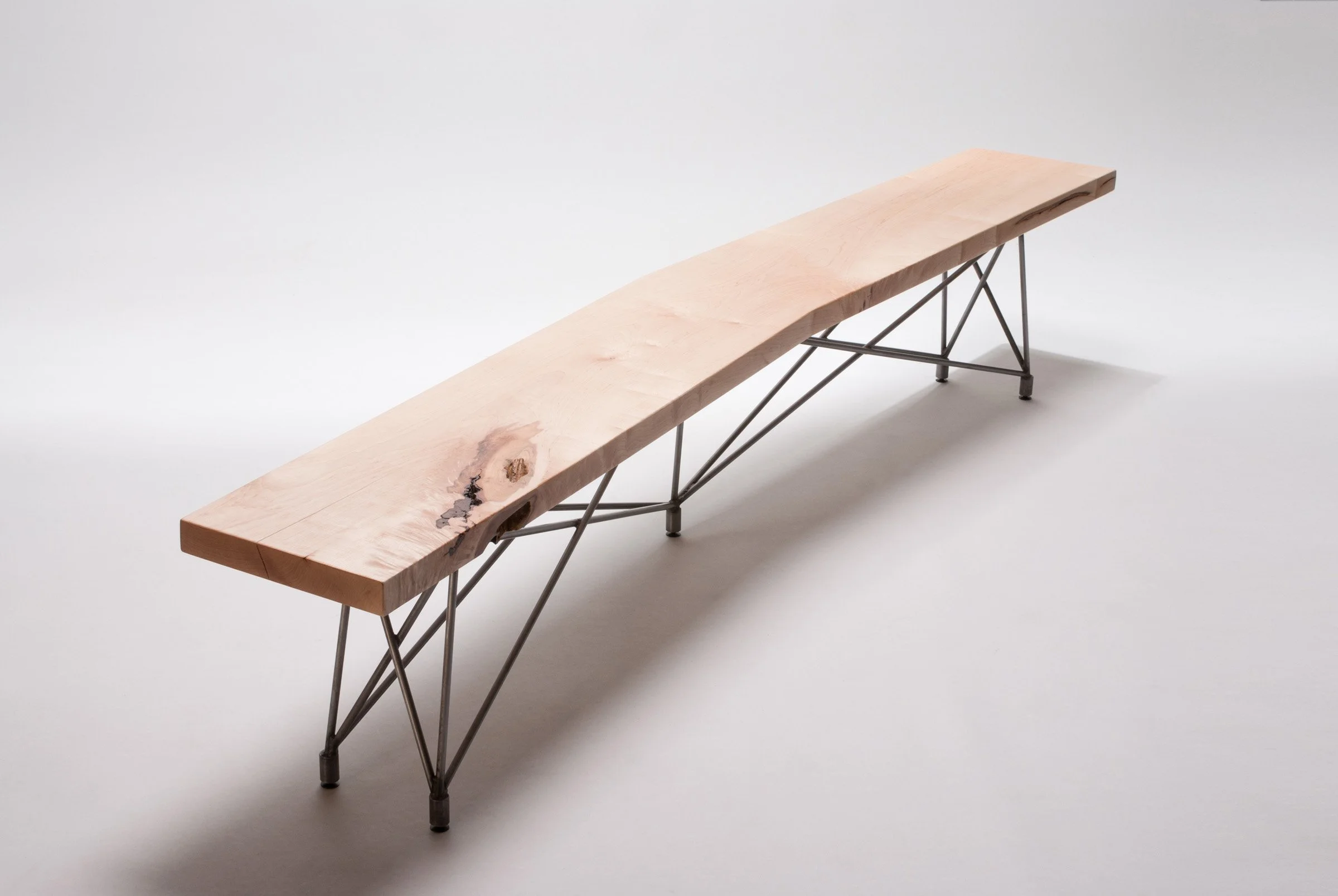 Handcrafted bench seating with natural wood tops and signature steel rod bases