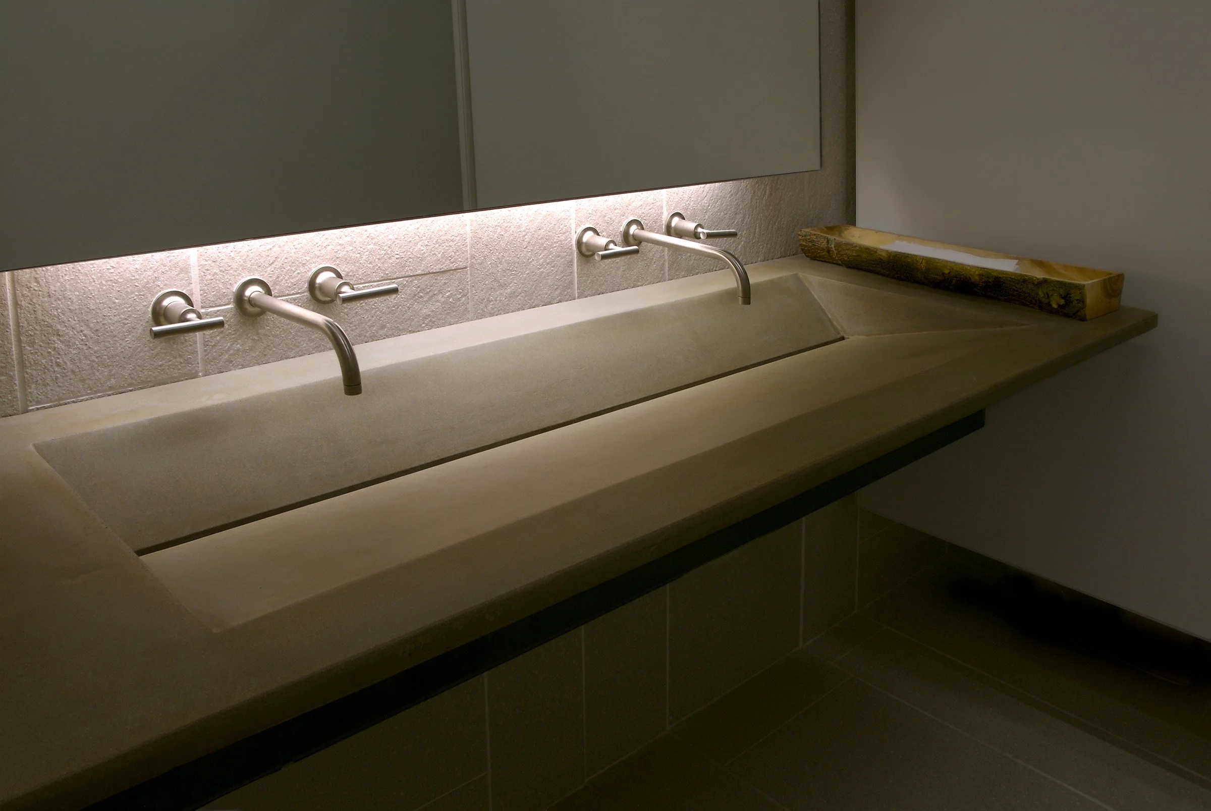 Custom concrete sink designed for high-capacity commercial bathrooms. Dual faucet ramp sink handcrafted in GFRC with a unique pre-aged tea-stain finish.
