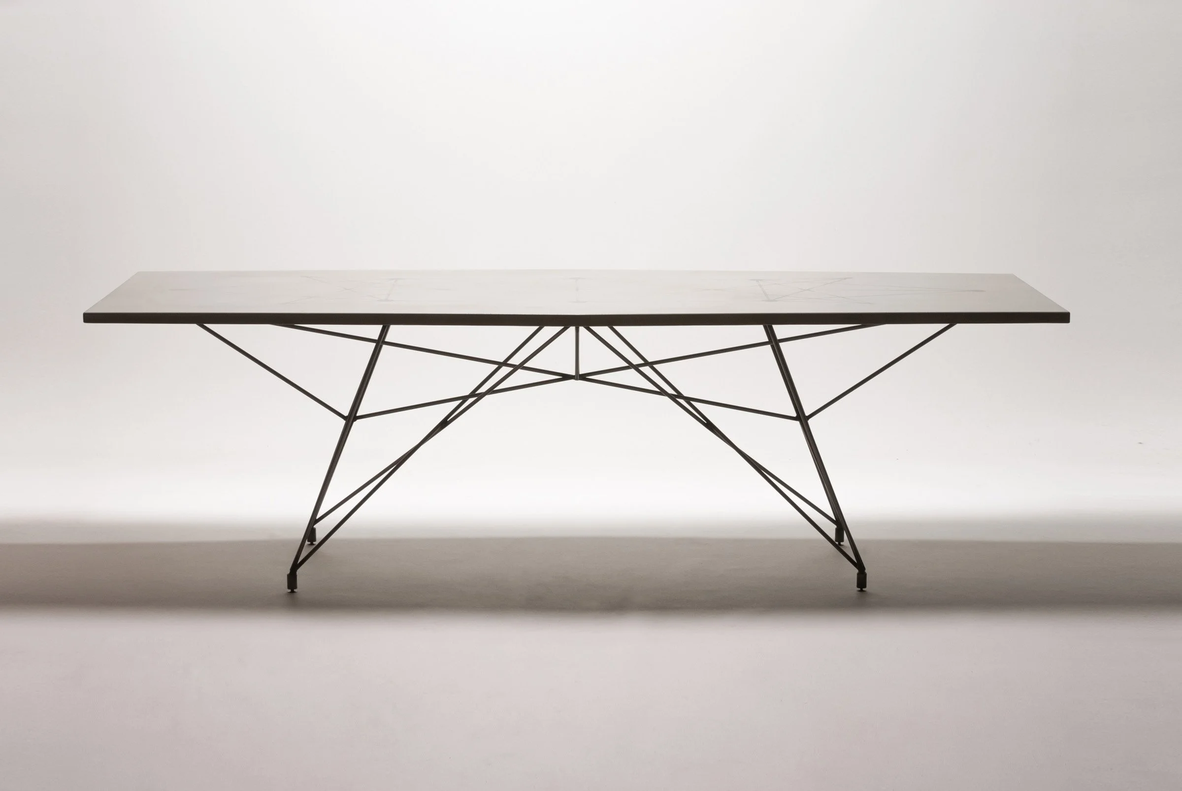 Handcrafted mid-century modern dining table in concrete and steel. Features etched tabletop design showing base structure, plus matching wood benches.