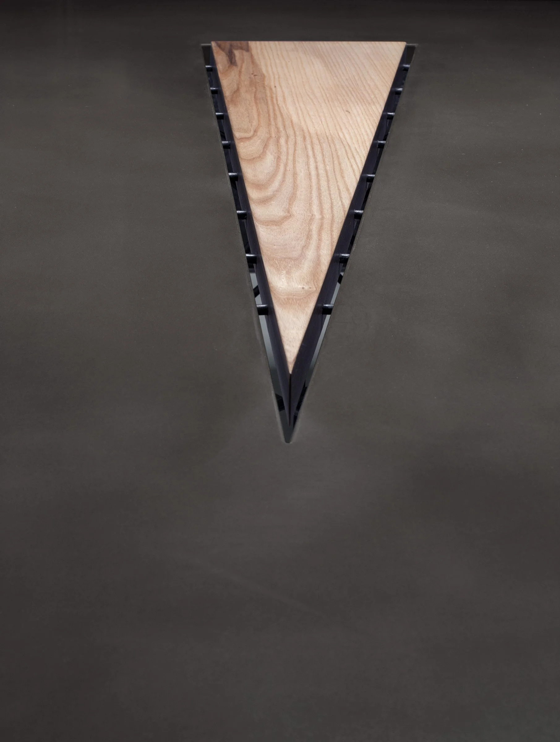 Triangular dining table with central wood island raised above concrete top