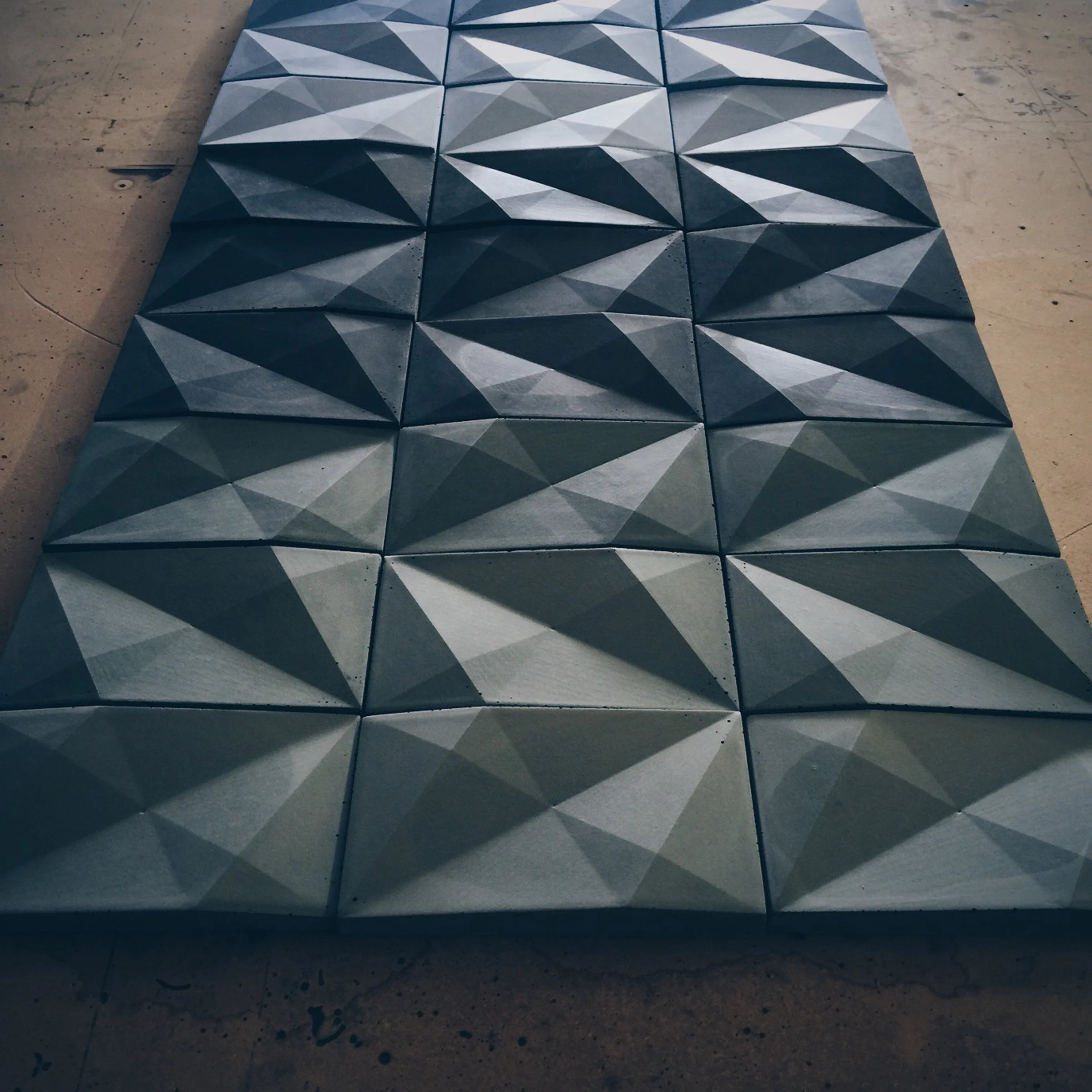 Architectural GFRC concrete tile with dynamic geometric facets.
