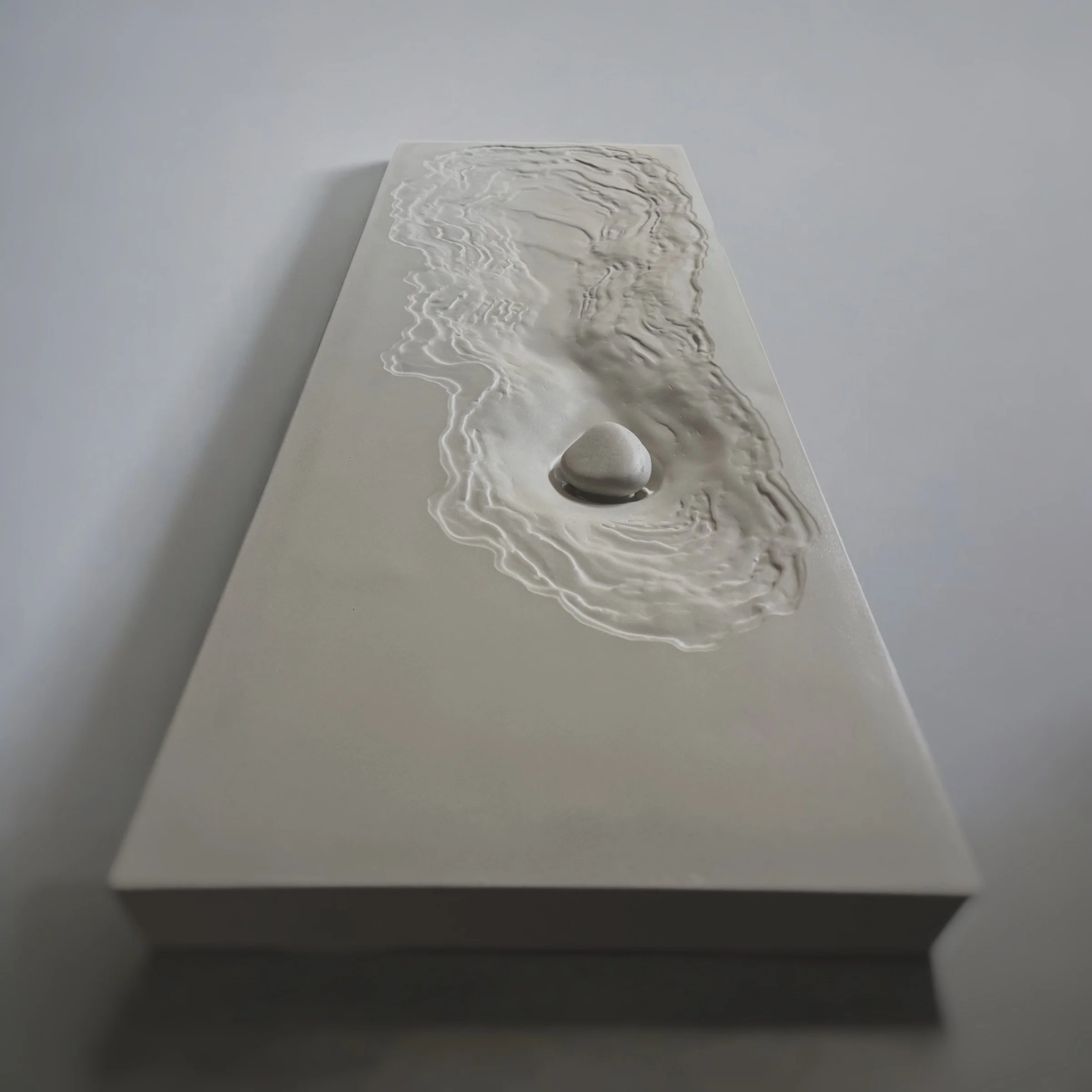 Luxury concrete bathroom sink where water flows beneath a concrete stone cover.