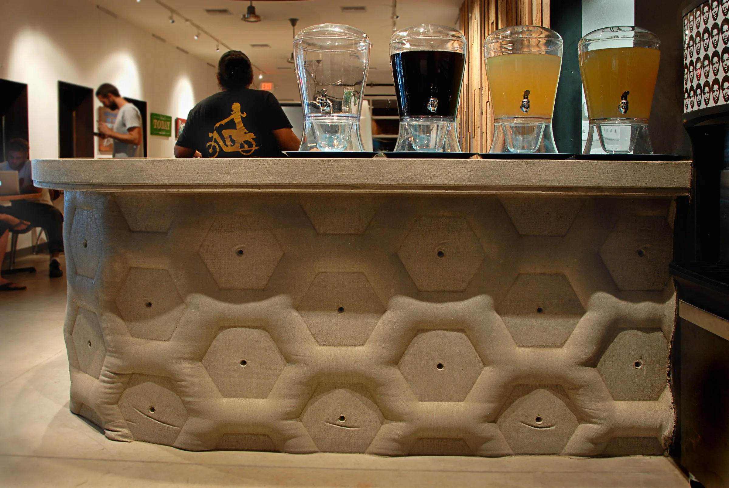 Fabric-formed concrete wall with hexagonal design for vegan restaurant interior