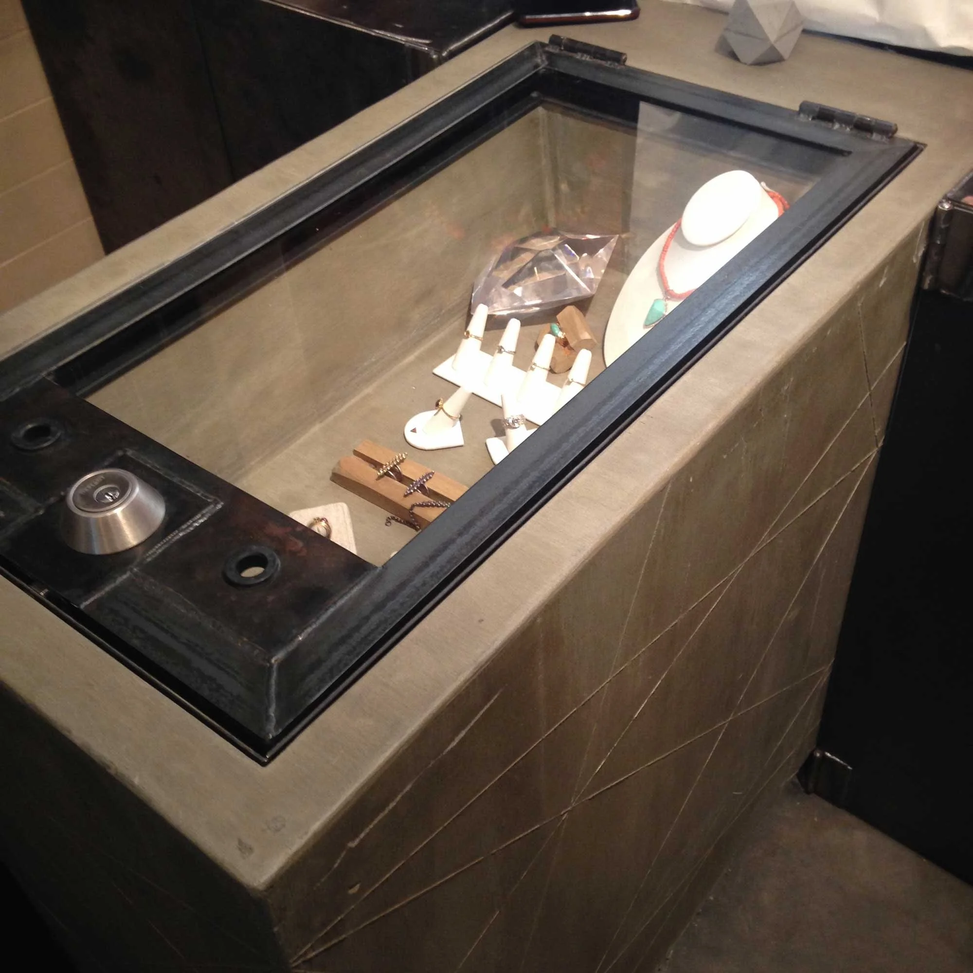 Handcrafted jewelry display case with geometric concrete texture.