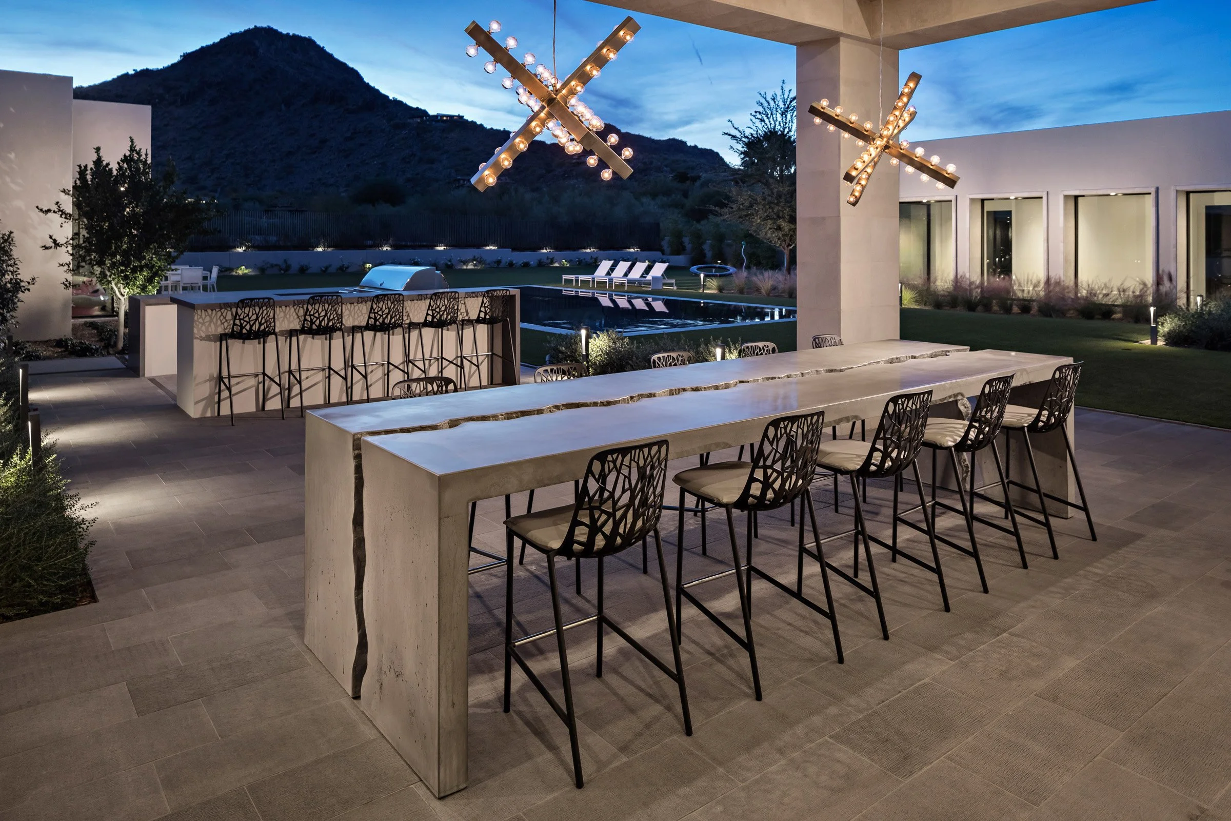 Custom outdoor bar-height dining table in fractured UHPC concrete. 13 feet long, 6 inches thick, post-tensioned for strength, and finished with food-safe sealer.