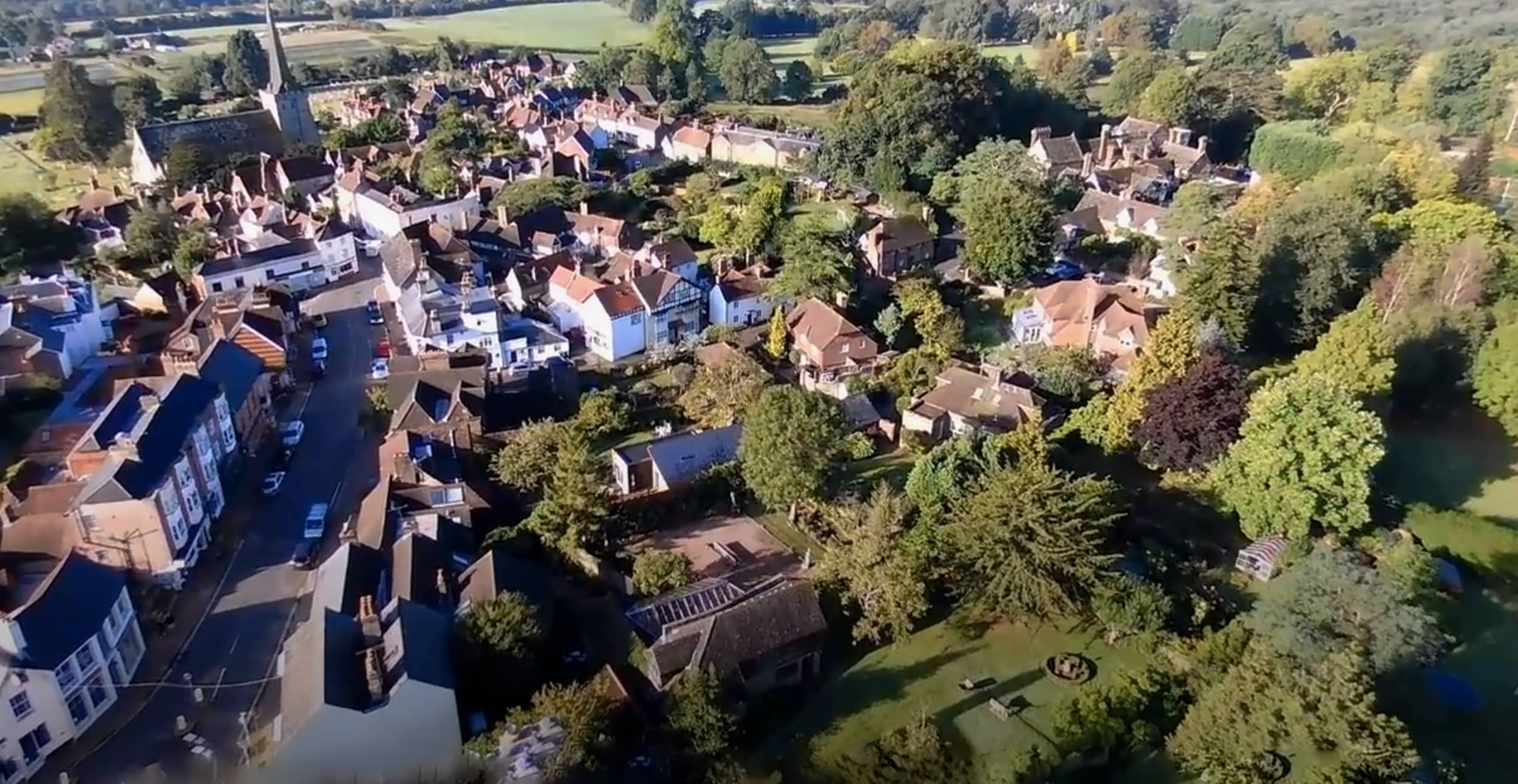 An aerial view of a small town with a mixture of houses, trees, and green spaces during daytime.