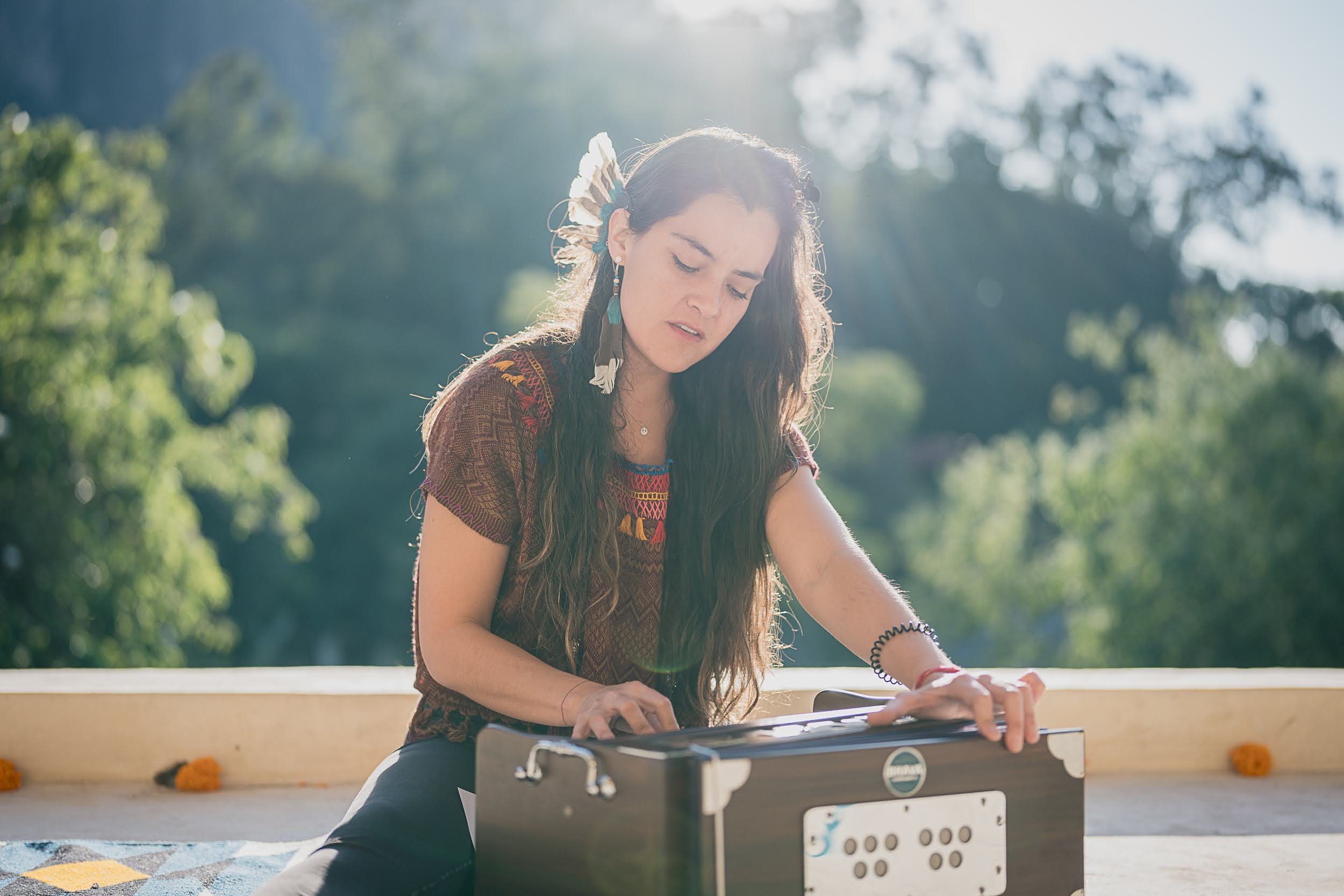 Jovencita tocando el teclado en un entorno natural al aire libre con árboles y luz solar