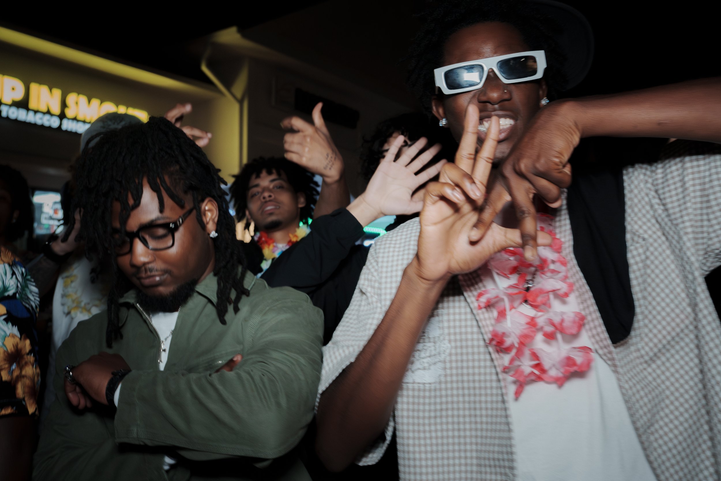 Group of people dancing and enjoying themselves at a party with colorful neon lights in the background.