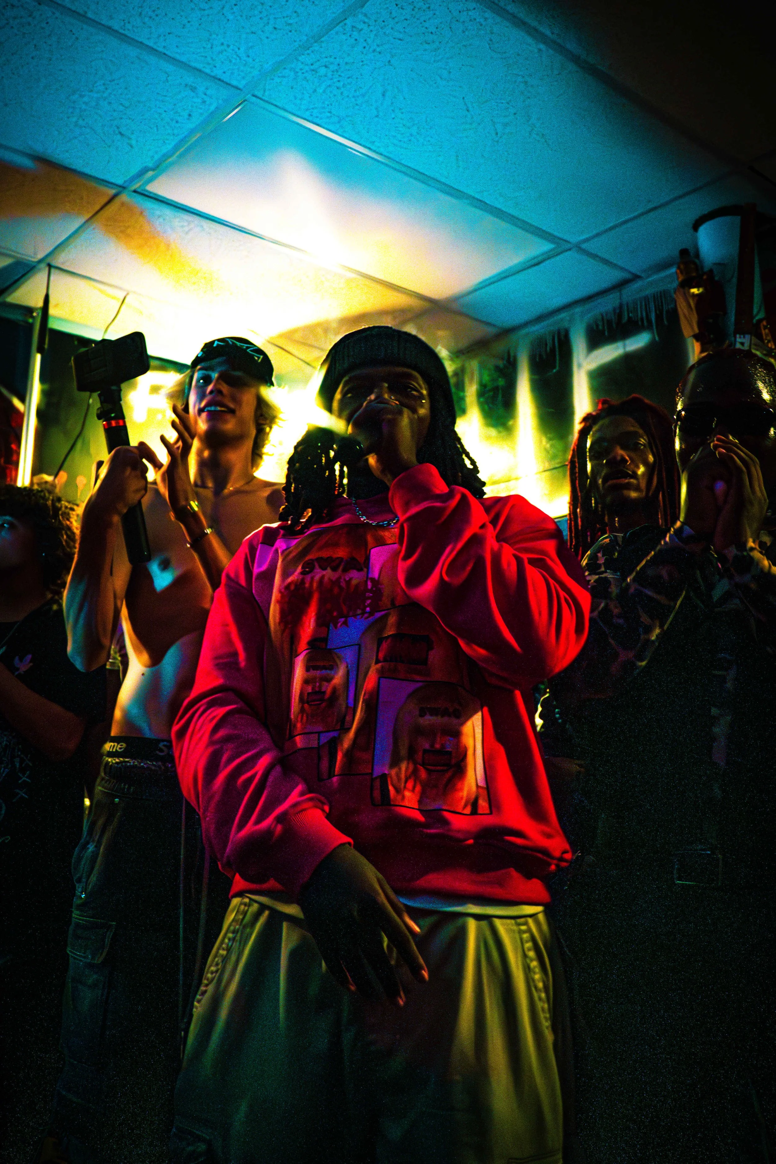 Group of people at a party or club dancing and taking photos with colorful lighting