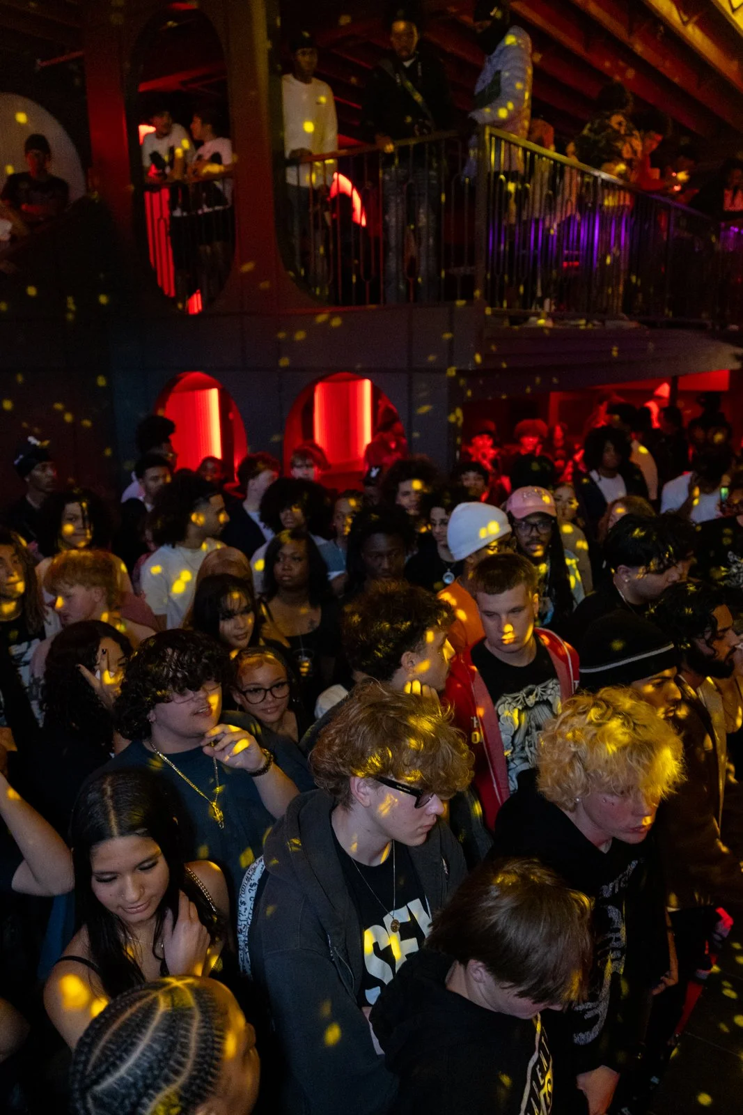 Crowd of people at a nightclub with colorful lighting and disco effects.