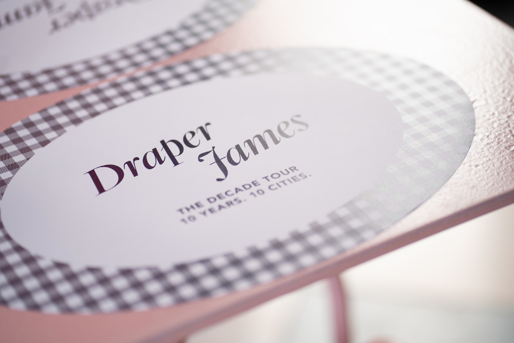 Draper James branded place settings feature navy gingham and Decade Tour language next to the classic logo