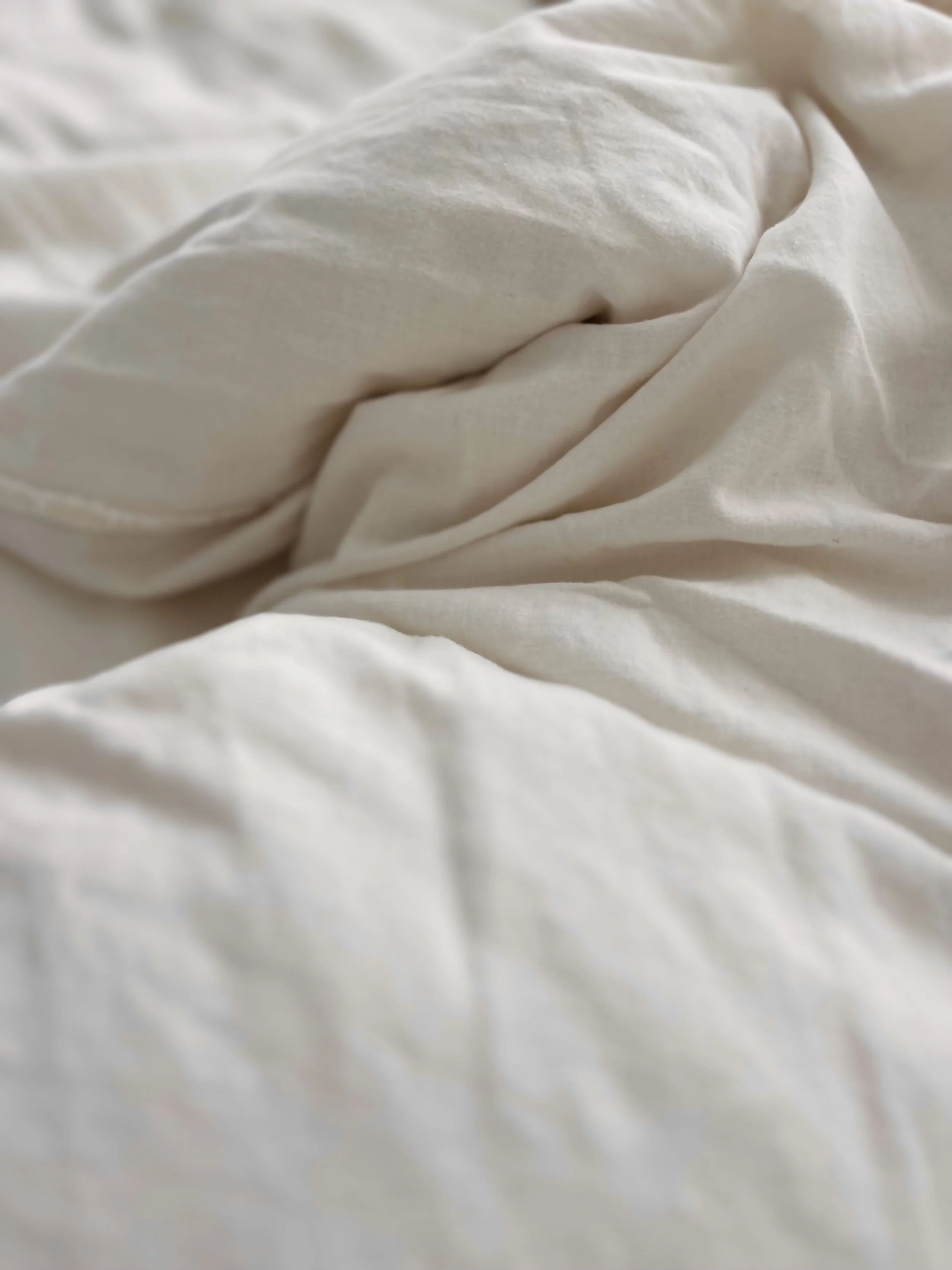 Close-up of white, wrinkled bedsheet or bedding fabric.