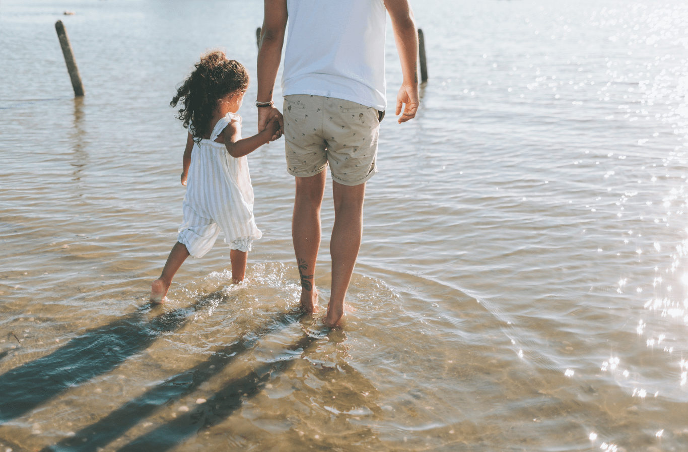 step Parent walking hand in hand with their child along the beach