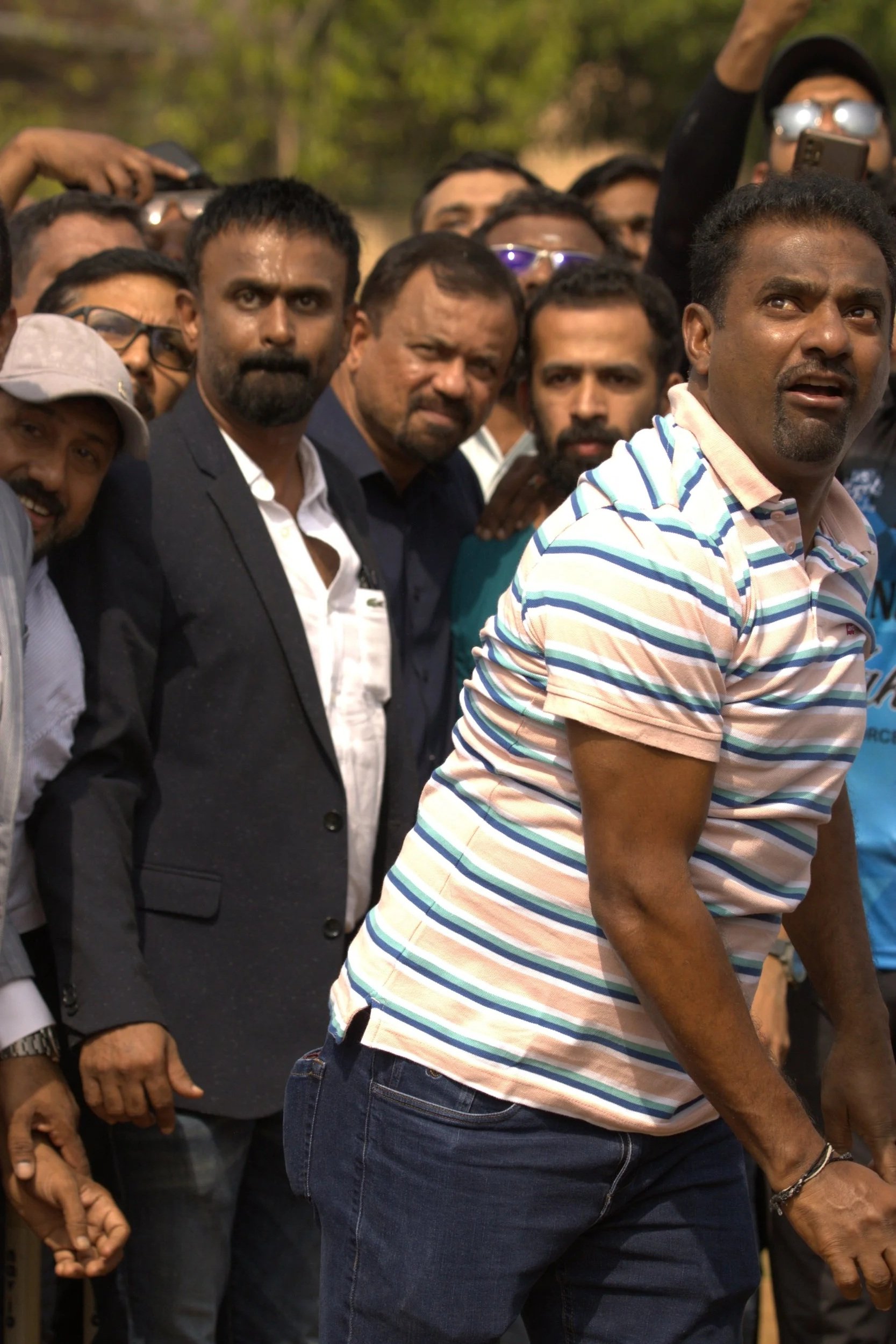 A group of men, some of whom are wearing formal and casual clothing, standing closely together outdoors during daytime.
