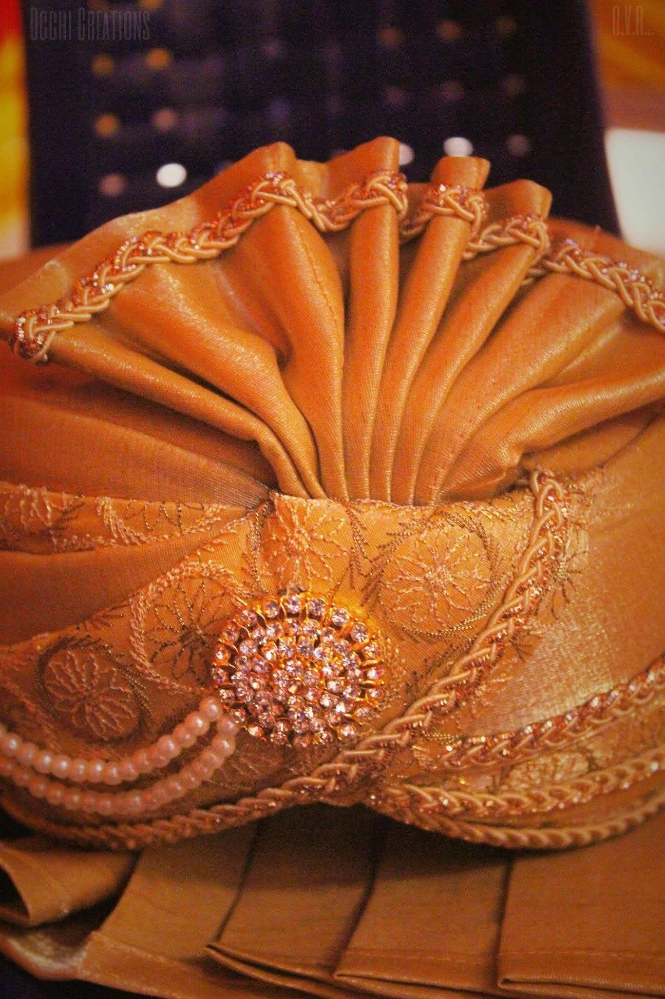 An elegant gold clutch purse with intricate embroidery and rhinestone embellishments, sitting on a wooden surface.