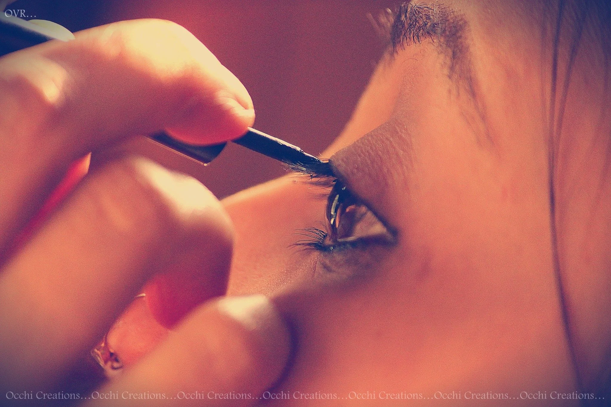 Close-up of someone applying eyeliner to their upper eyelid with a brush.