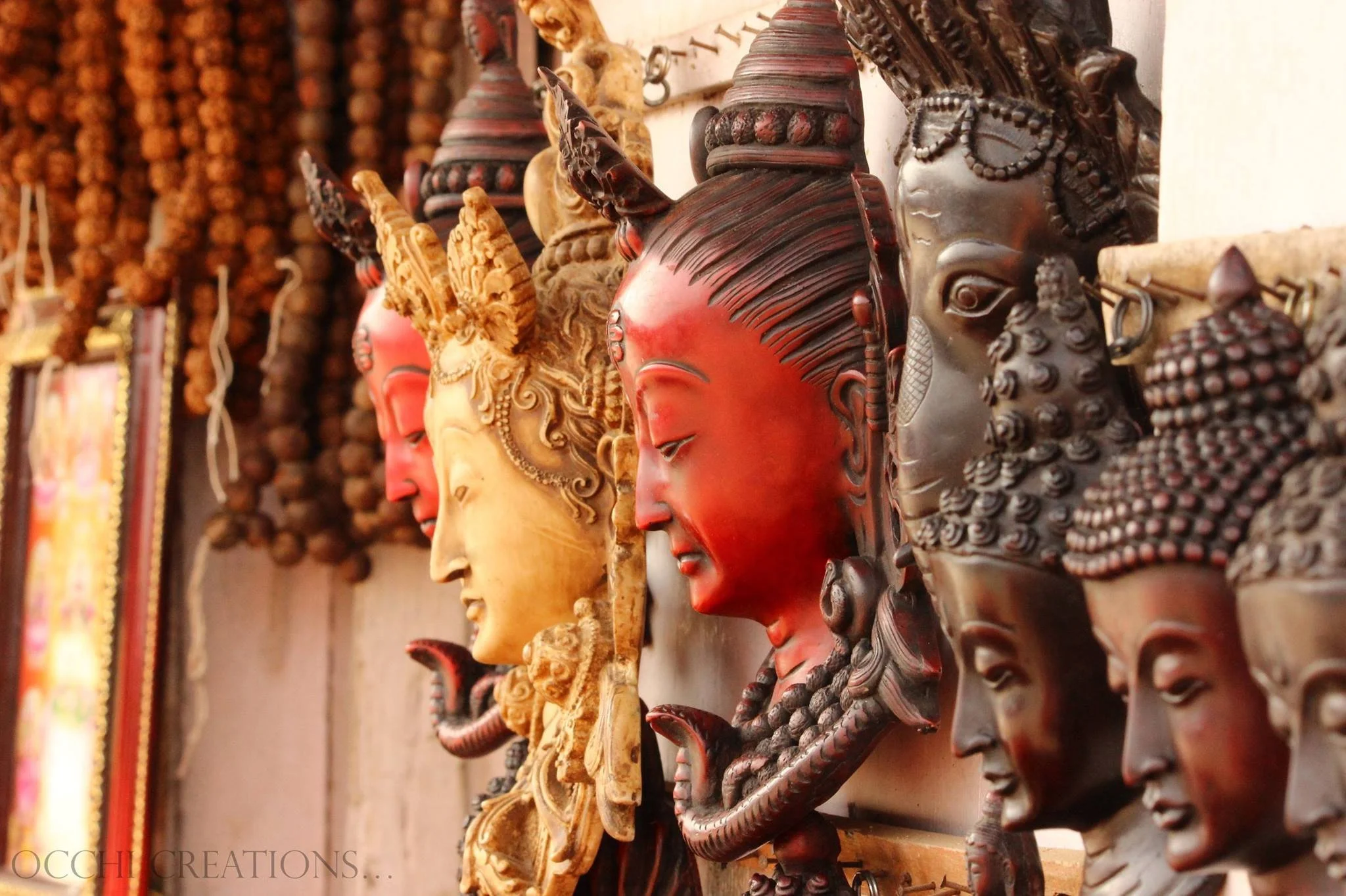 Row of colorful wooden masks with intricate carvings, displayed on a wall in a shop.