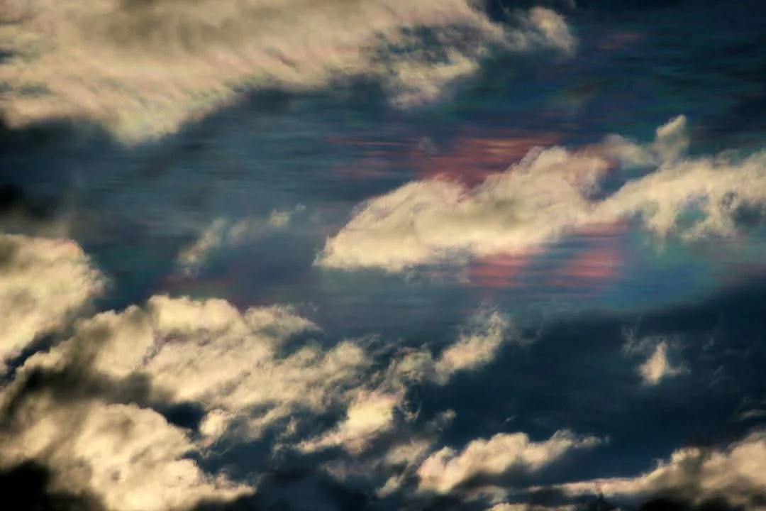 Cloudy sky with dark and light clouds and hints of pink sunlight.