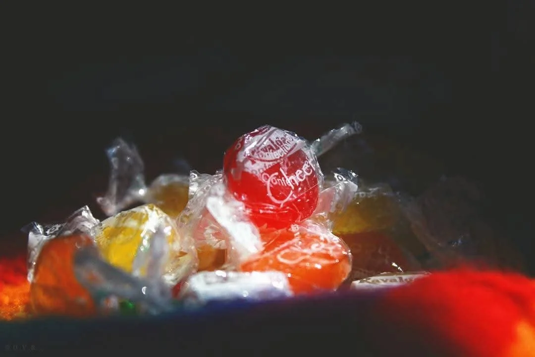 A close-up of assorted individually wrapped candies in various colors, including red, yellow, and orange.