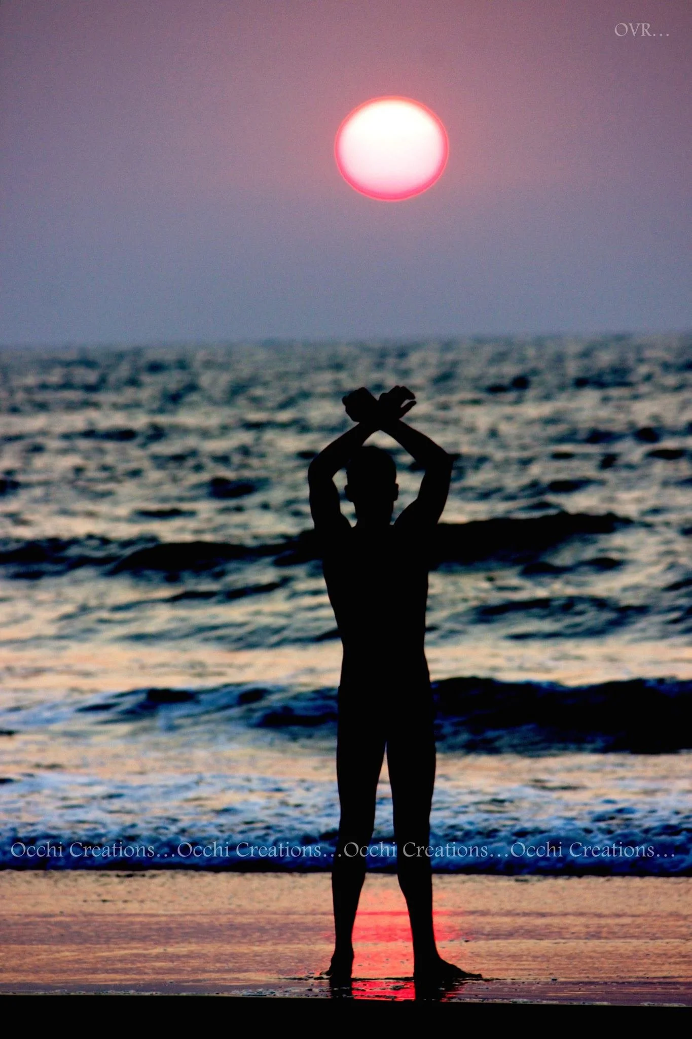Silhouette of a person standing on the beach at sunset with arms crossed above their head, ocean waves in the background, and a pink sun in the sky.