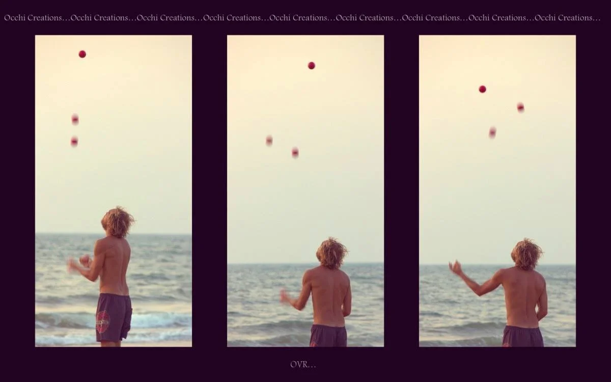 A young man with curly hair and no shirt, wearing shorts, stands on a beach and juggles three red balls against the sky and ocean.