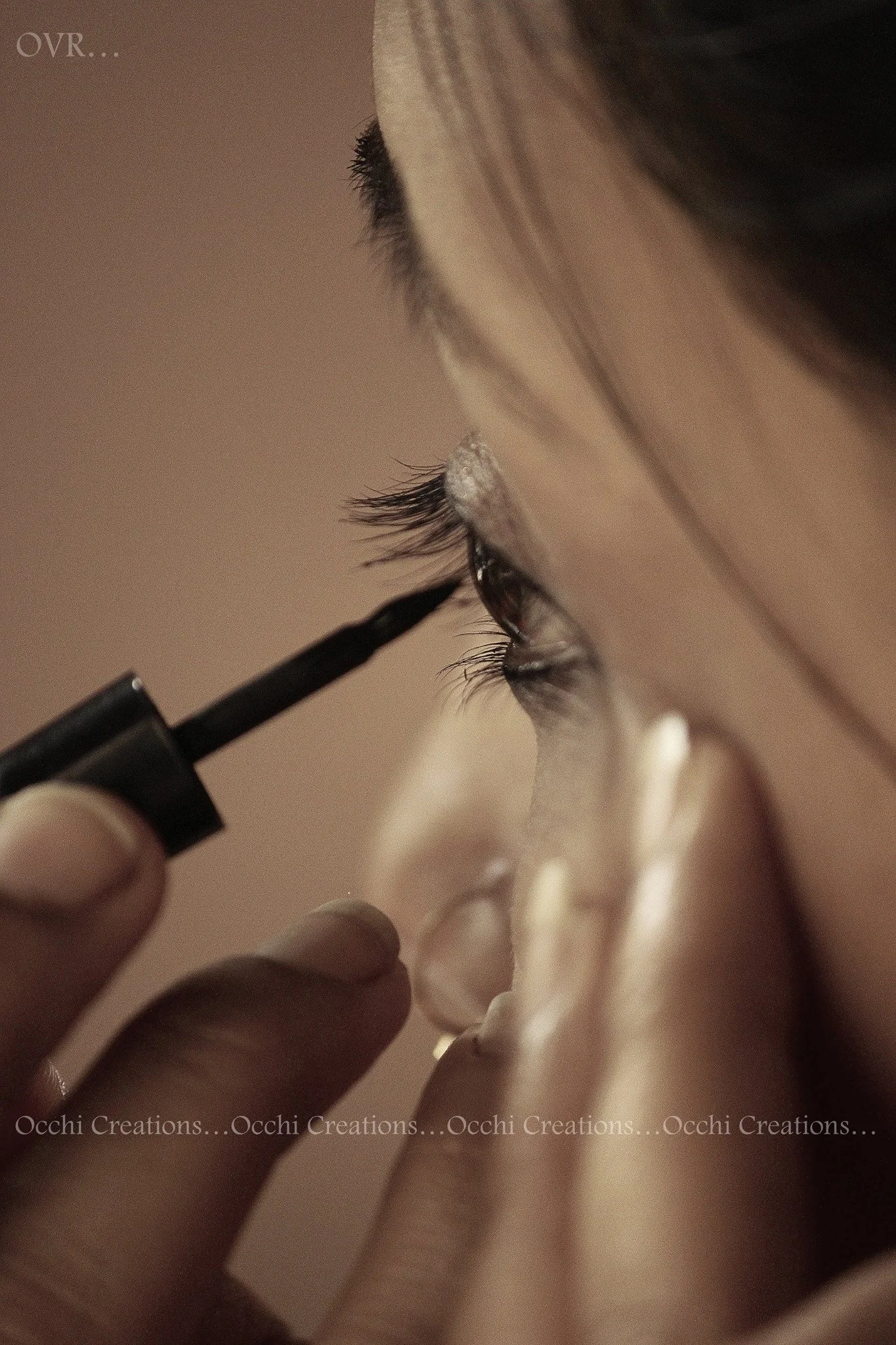 A person applying makeup with a black eyeliner pencil to their eyelid, focusing on the eye area.