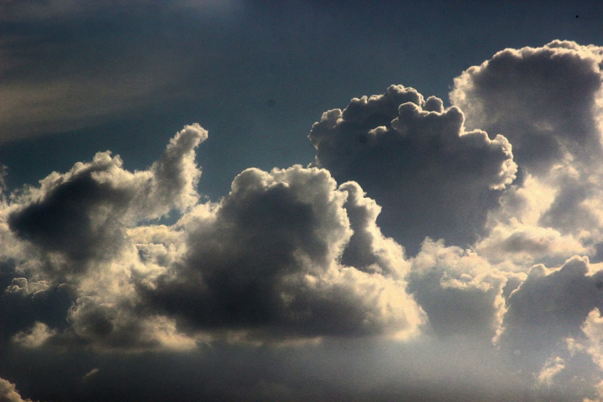 Dark sky with large, fluffy clouds illuminated from behind.