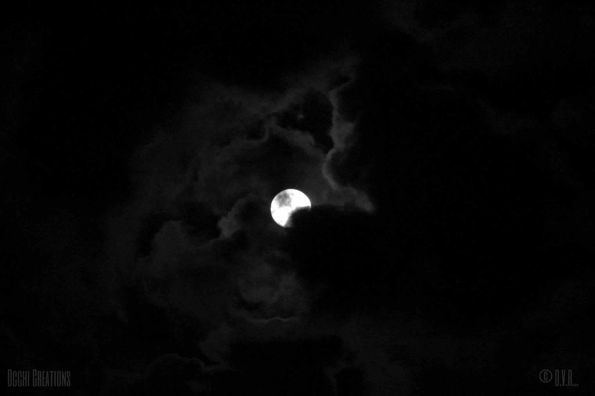 Full moon shining through dark clouds in the night sky