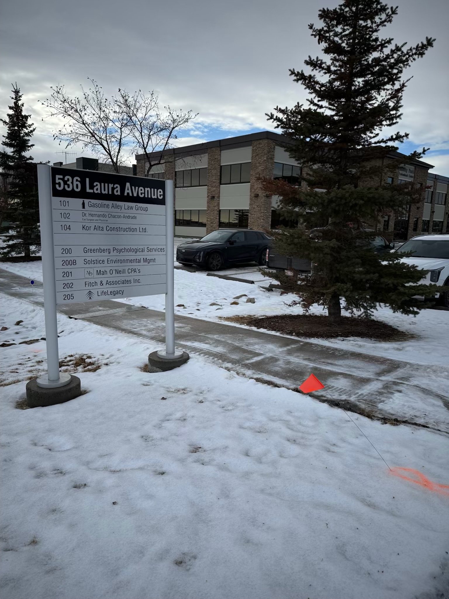 A sign in front of a building at 536 Laura Avenue, listing business names including Gasoline Alley Law Group, Dr. Hernando Chacon-Andrade, Kor Alta Construction Ltd., Greenberg Psychological Services, Solstice Environmental Mgmt, Mah O’Neill CPA's, F